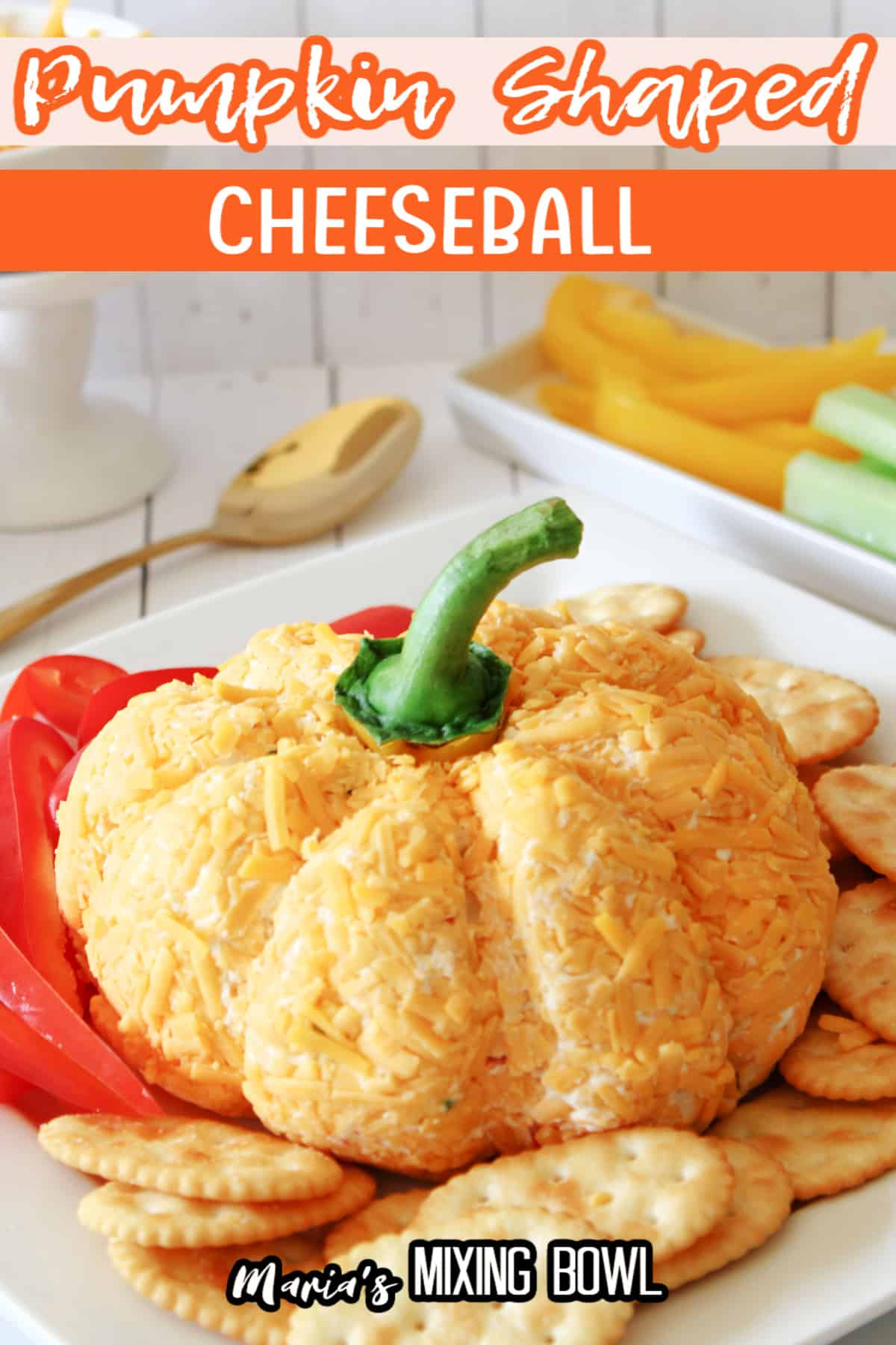 pumpkin shaped cheese ball on a plate with bell pepper slices and crackers.