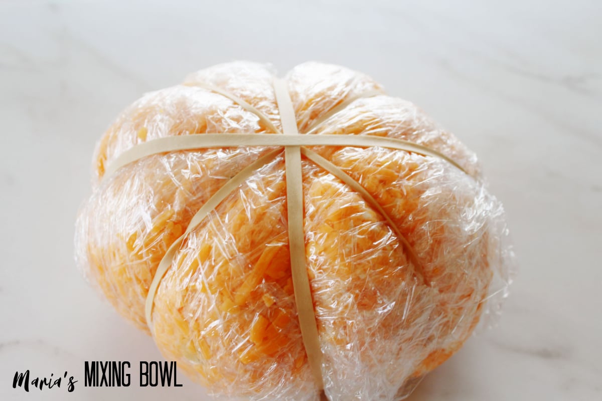 cheese ball wrapped with plastic wrap and rubber bands to make a pumpkin shape.