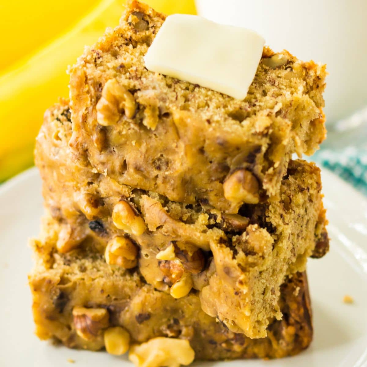 three slices of banana bread on a plate with a pat of butter on the top.