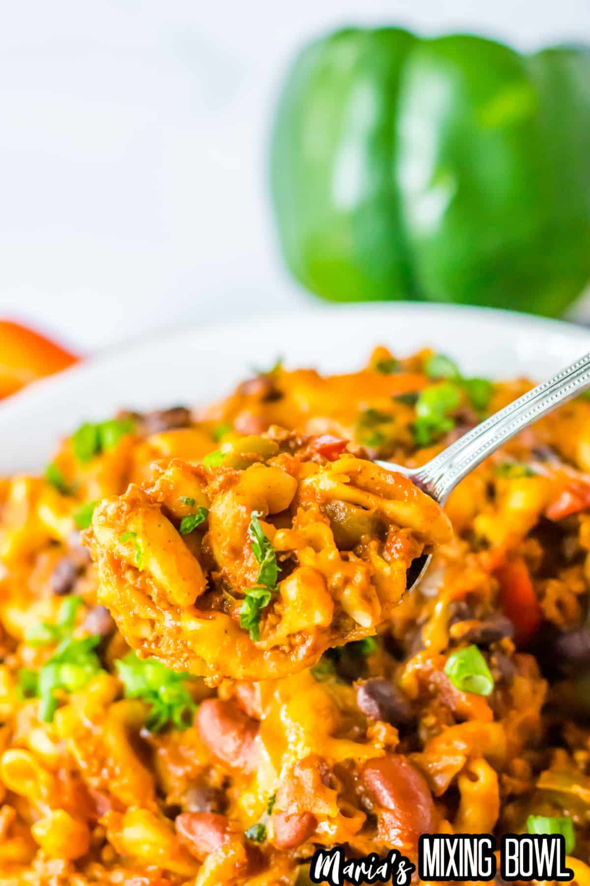 spoonful of chili mac held in the air above a bowl full of mac.