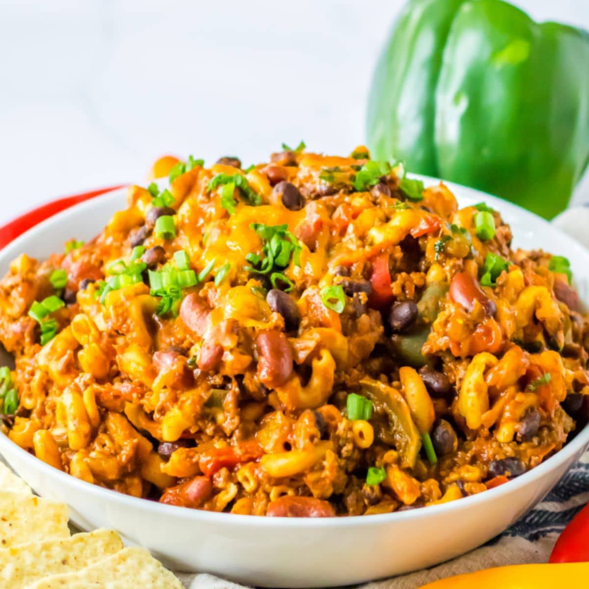 bowl full of chili mac garnished with green onions.