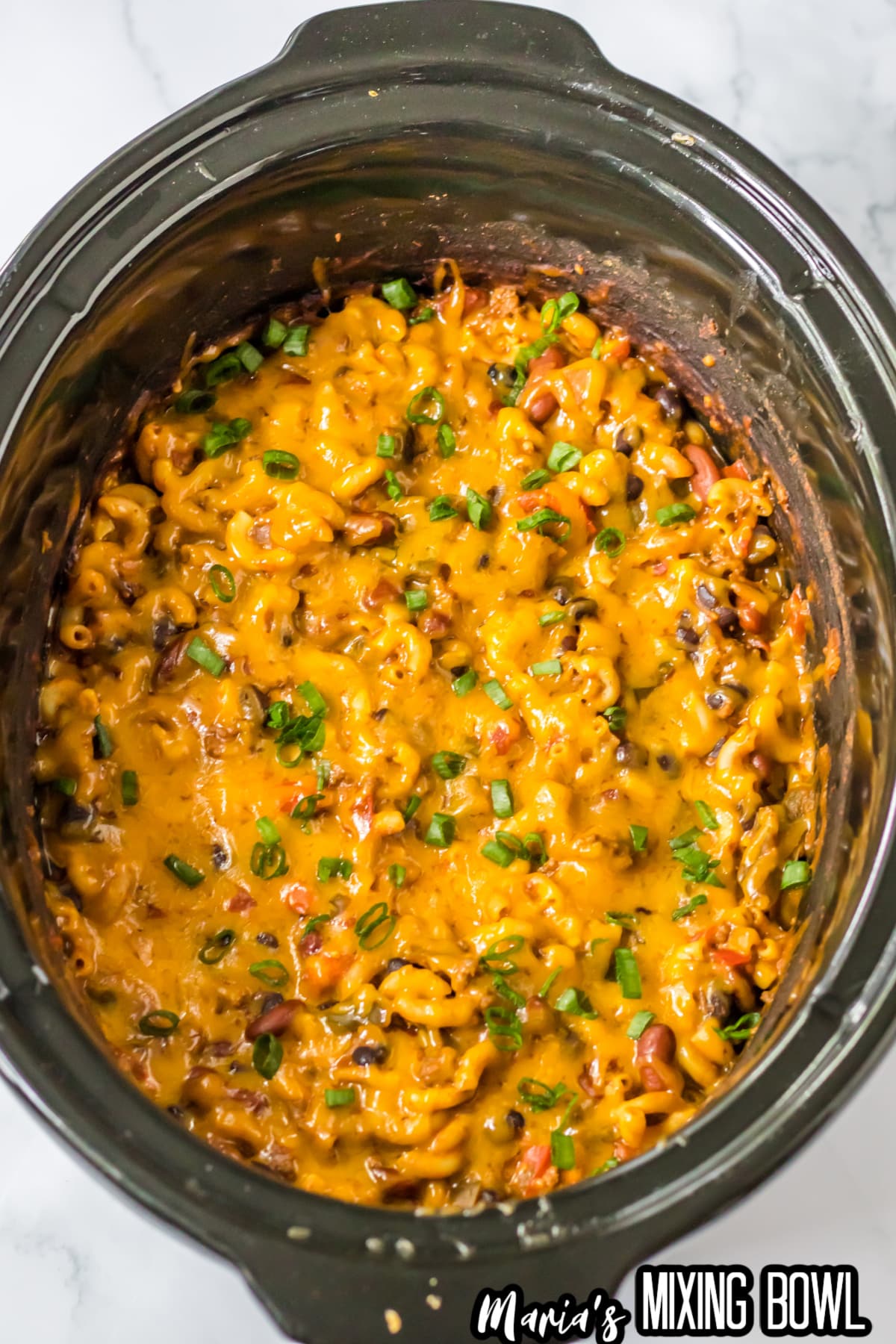 cooked chili mac with melted cheese on the top in slow cooker.