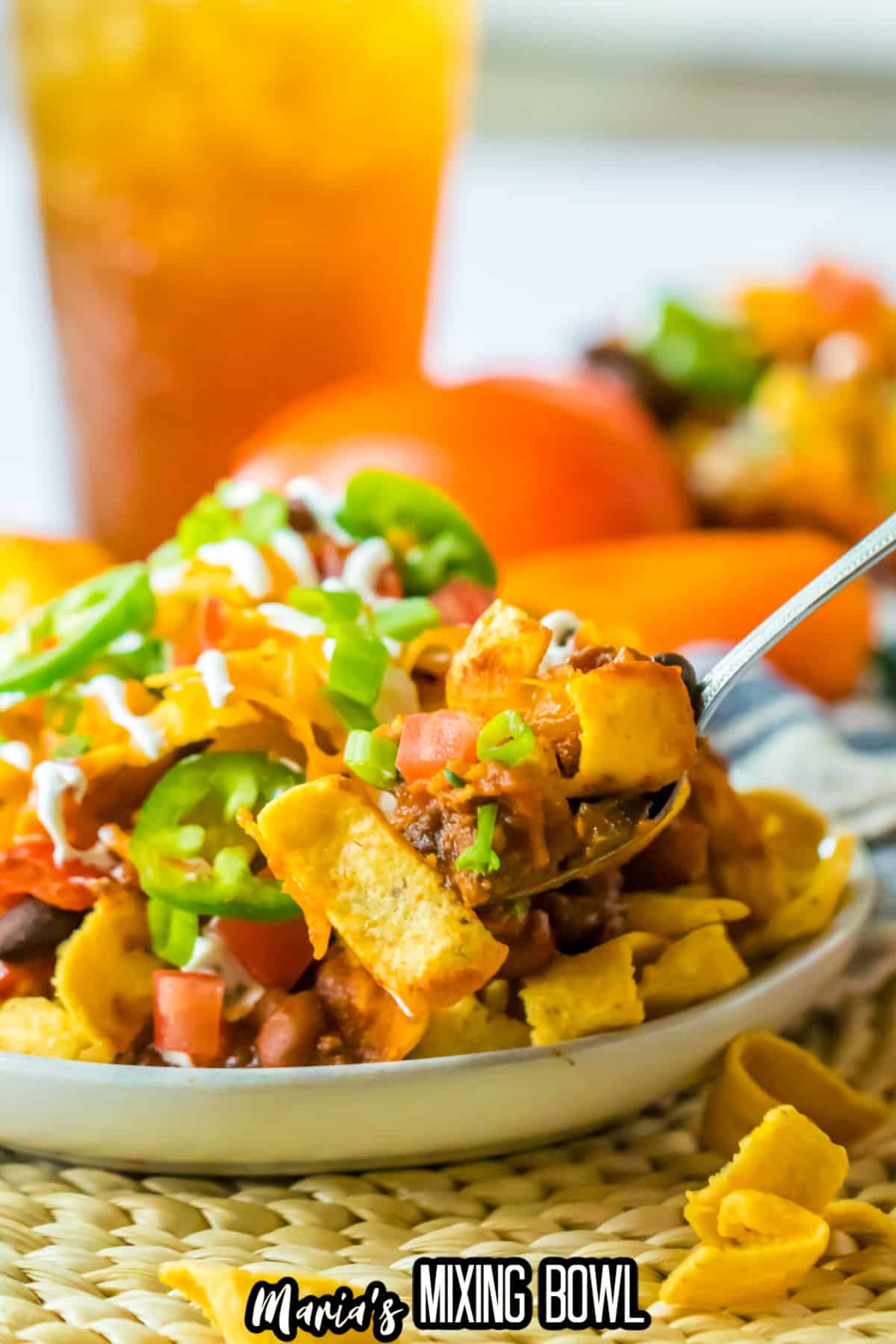 plate full of frito pie and topped with jalapeno slices and sour cream.