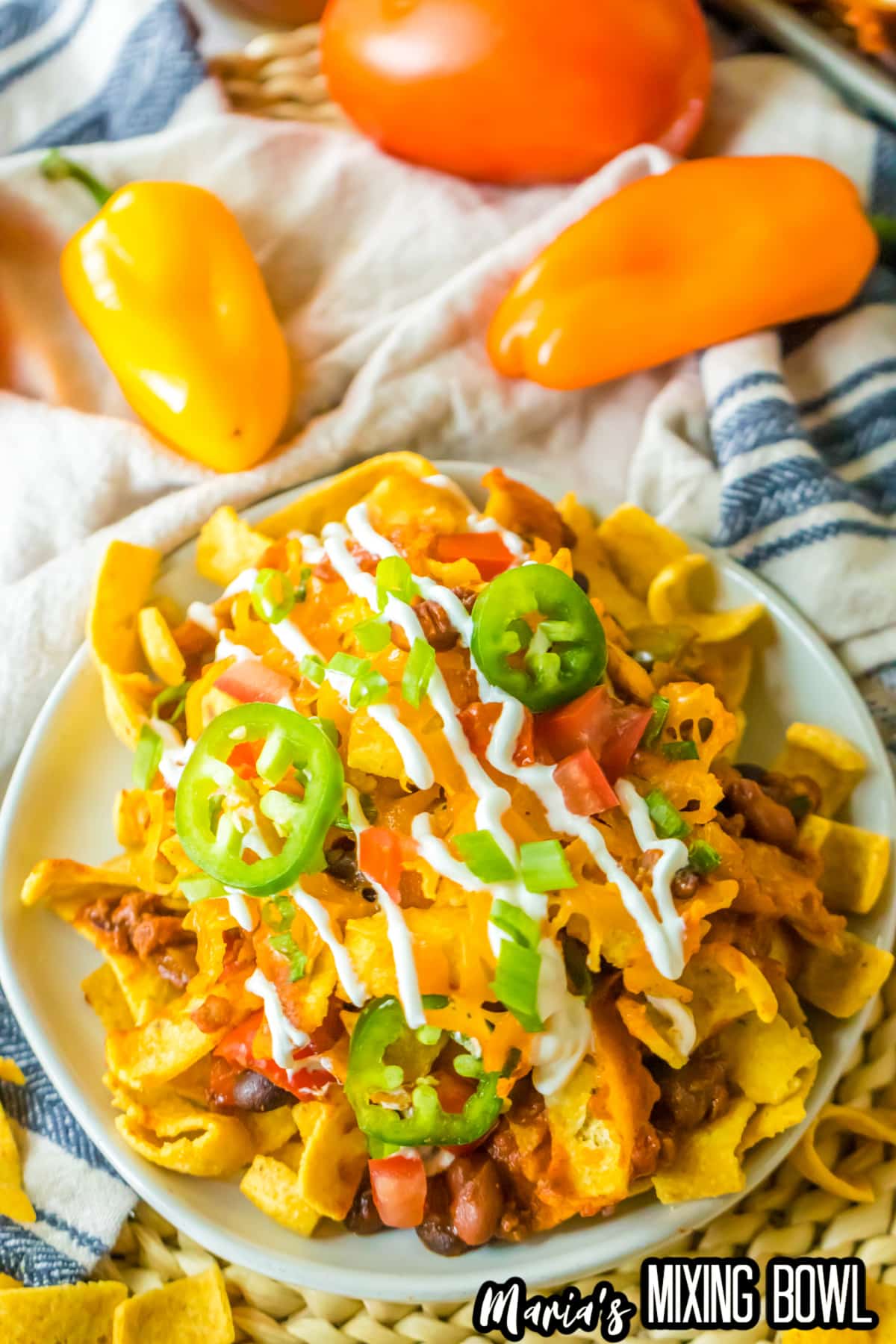 plate full of frito pie and topped with jalapeno slices and sour cream.