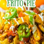 plate full of frito pie and topped with jalapeno slices and sour cream.