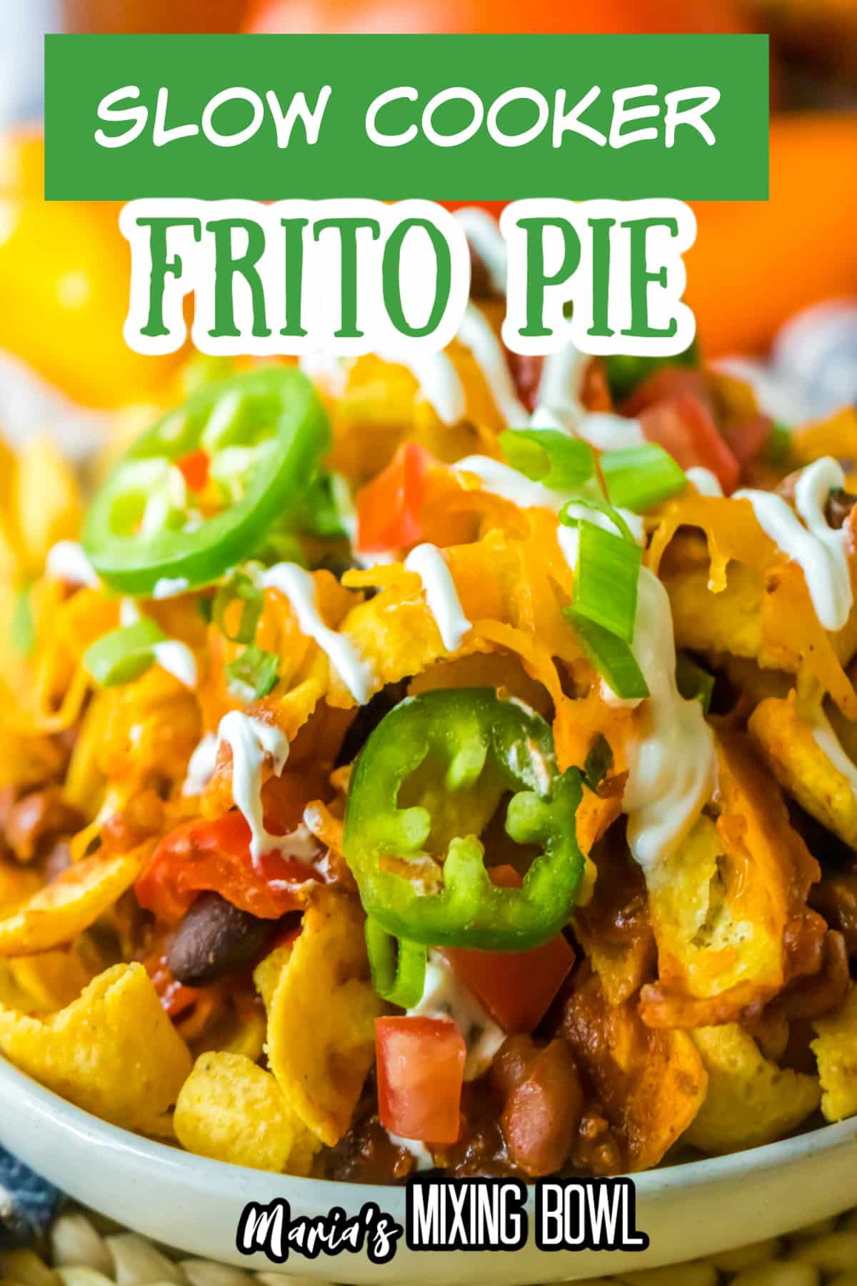 plate full of frito pie and topped with jalapeno slices and sour cream.