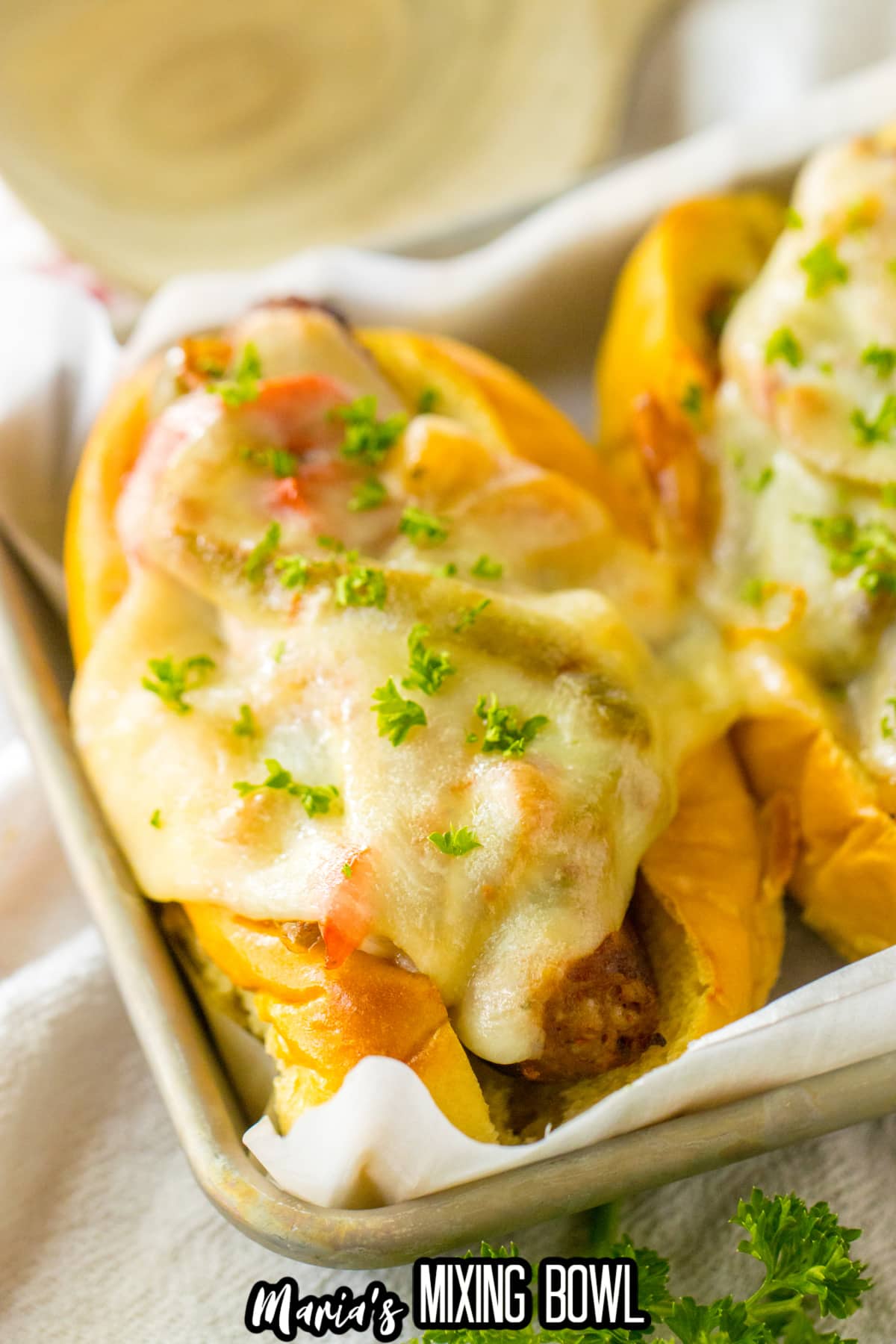 sausage and peppers on a hoagie roll with melted cheese on top.