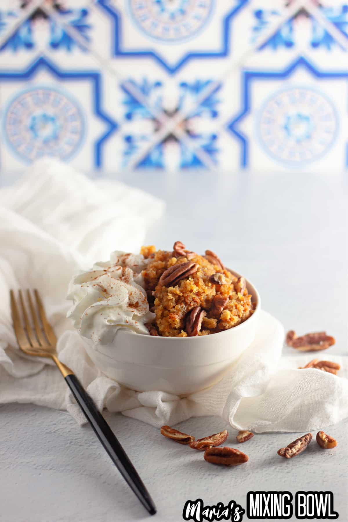 bowl full of slow cooker pumpkin cobbler topped with whipped cream.