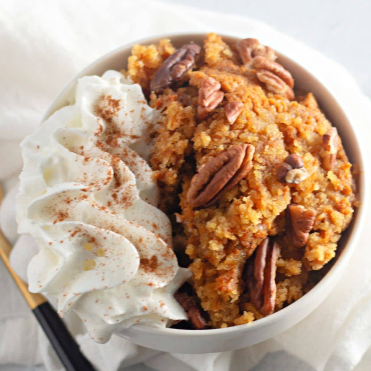 bowl full of slow cooker pumpkin cobbler topped with whipped cream.