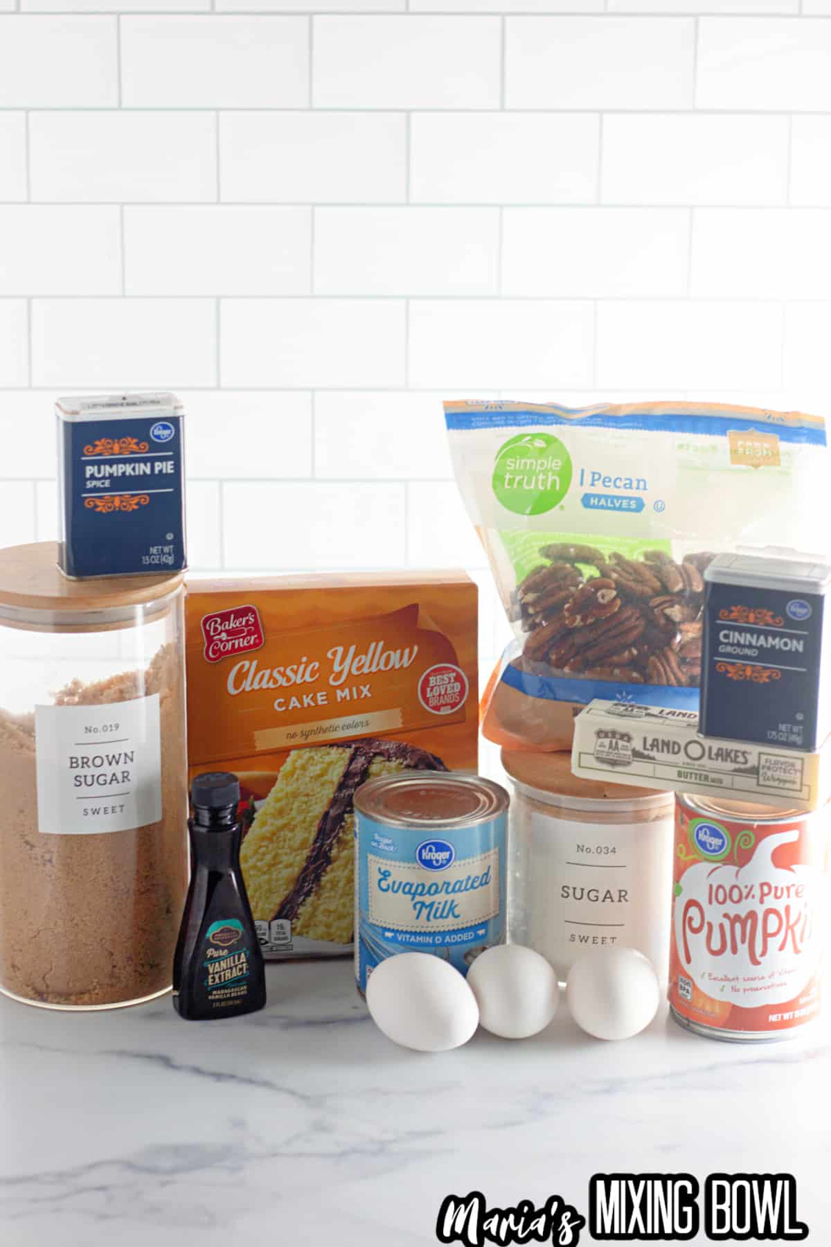 containers of pumpkin pie spice, brown sugar, cake mix, vanilla extract, evaporated milk, eggs, pecans, cinnamon, sugar, butter, and pumpkin puree.