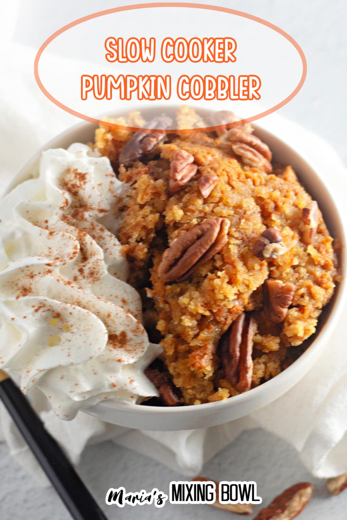 bowl full of slow cooker pumpkin cobbler topped with whipped cream.