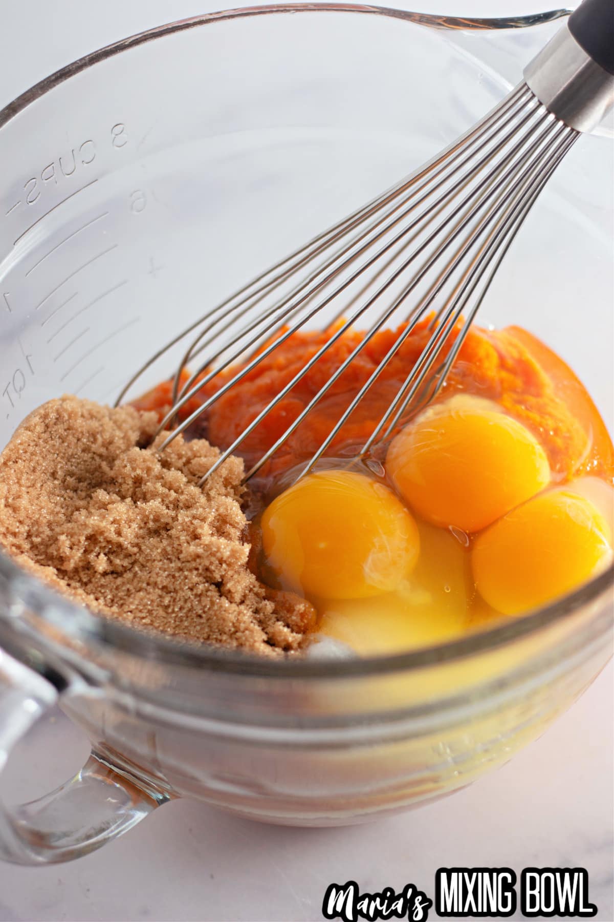 eggs, brown sugar, sugar, and pumpkin in a glass mixing bowl.