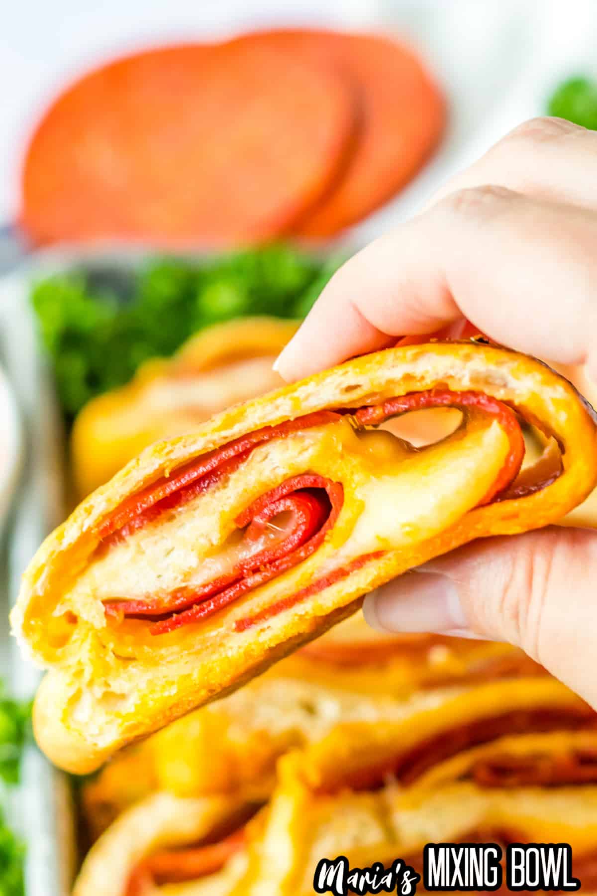 slice of stuffed pepperoni bread held in a womans hand in the air.