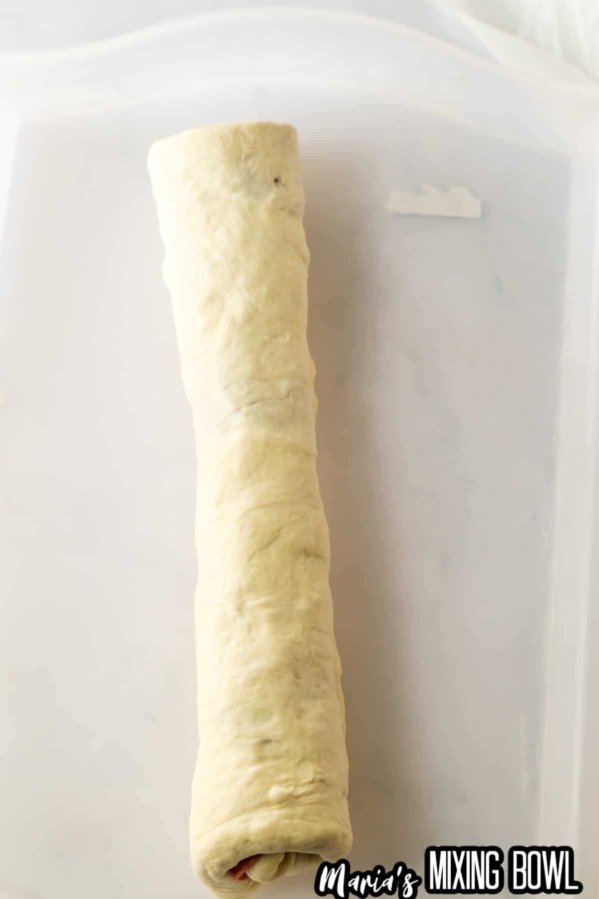 roll of stuffed pepperoni bread on a parchment baking sheet