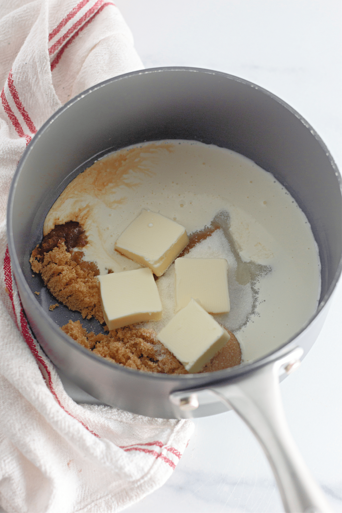 butter, brown sugar and heavy cream being melted in a saucepan.