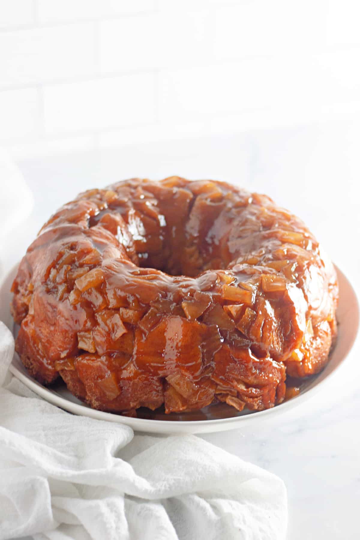 uncut apple pie monkey bread on a cake plate.