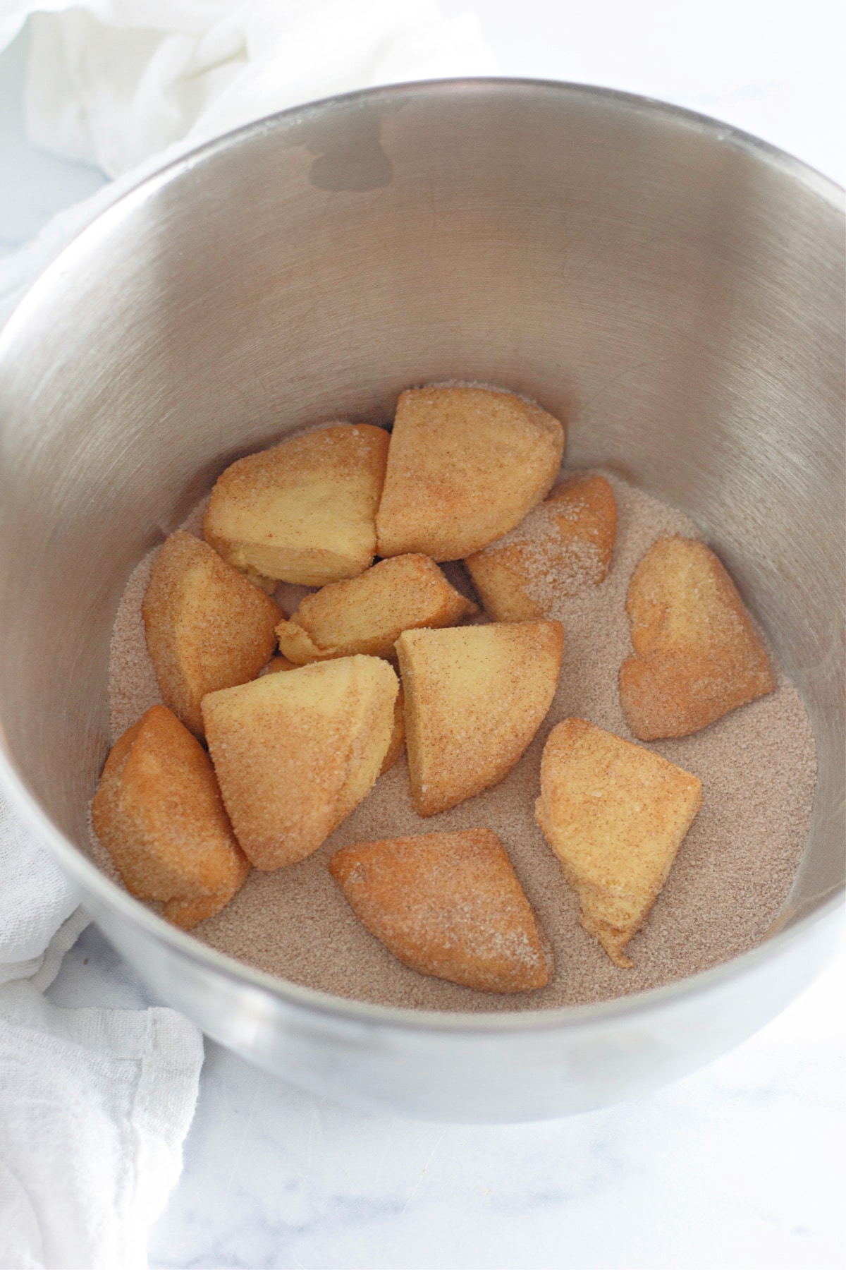 donut pieces being tossed in a cinnamon sugar mixture.