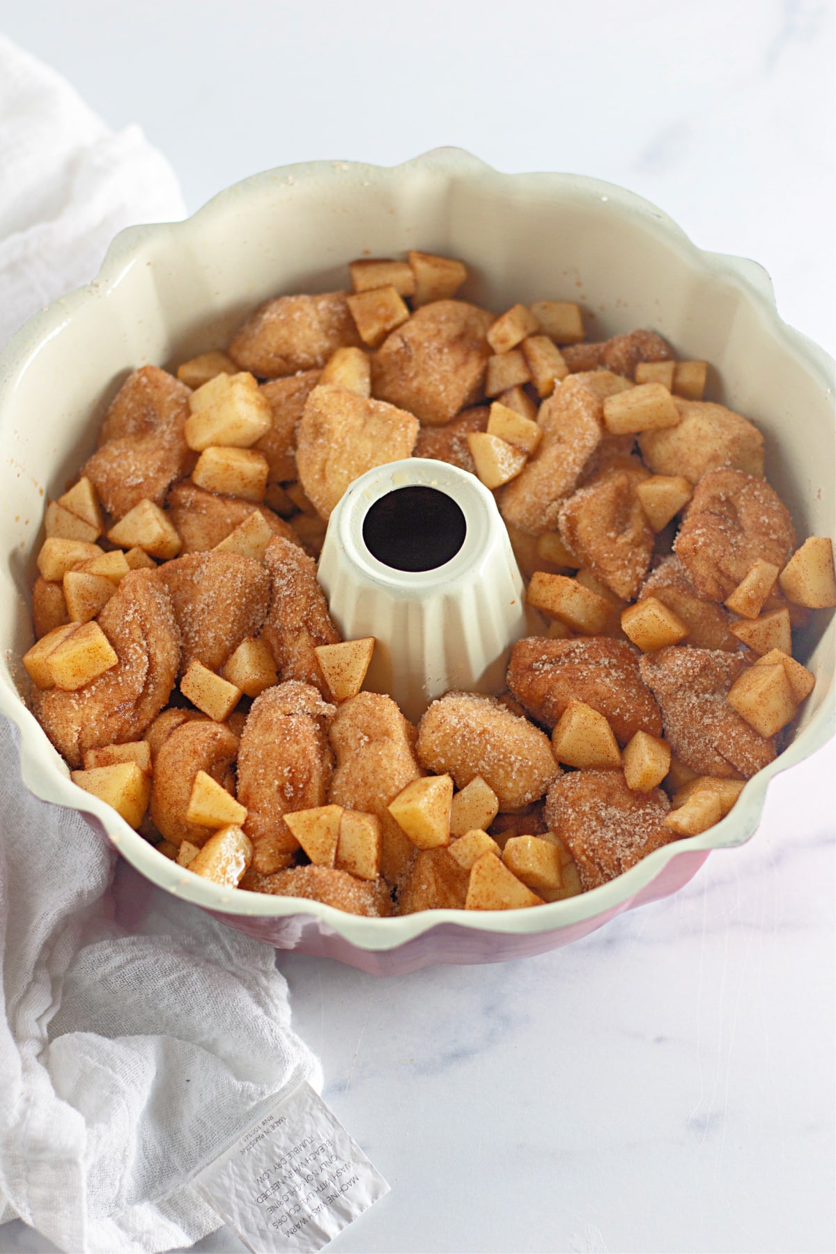 apple pie monkey bread being layered in a bundt pan.