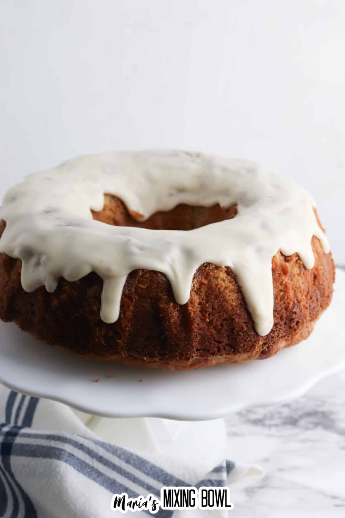 uncut frosted apple spice cake on a cake stand.