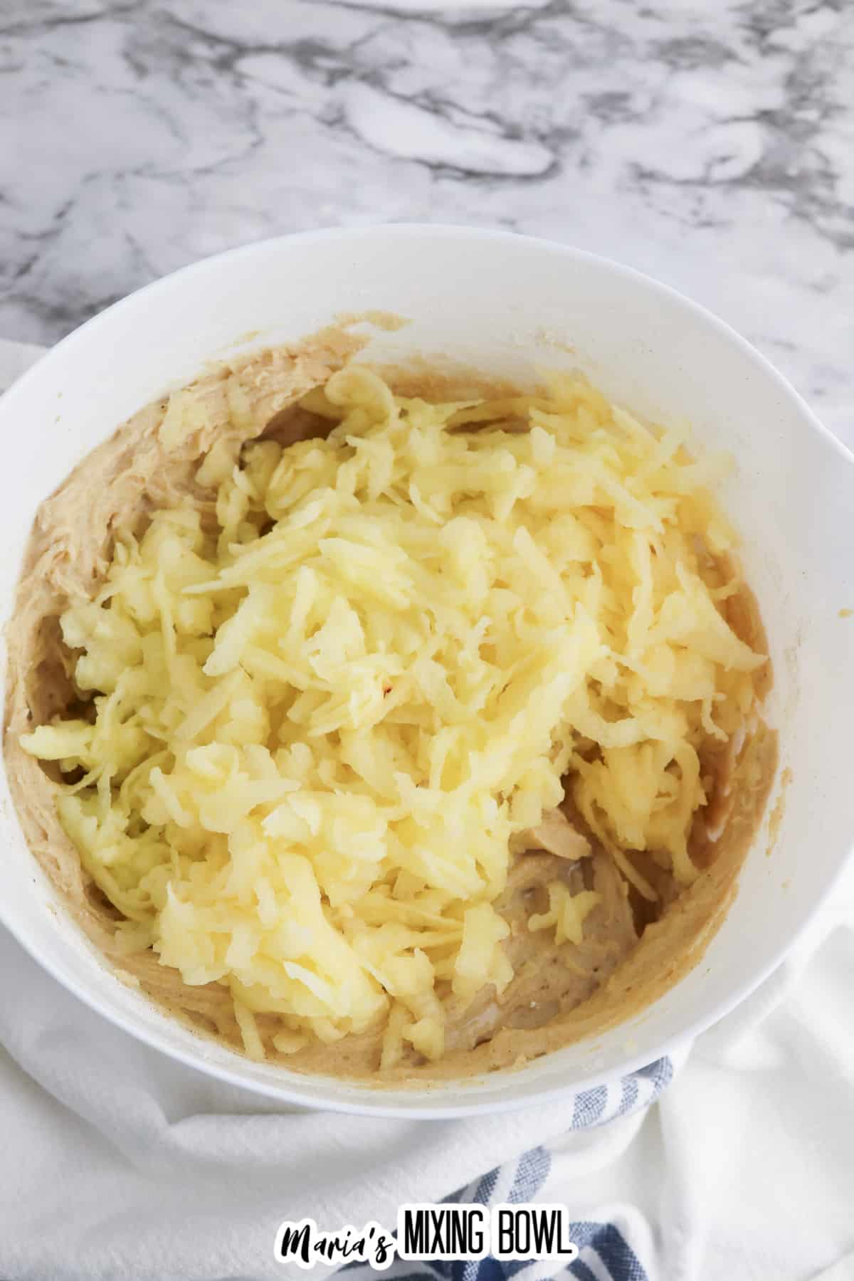 shredded apples being added to the cake batter.