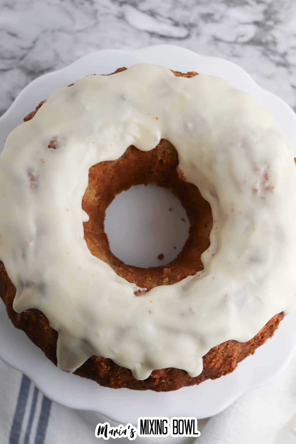 uncut frosted apple spice cake on a cake stand.