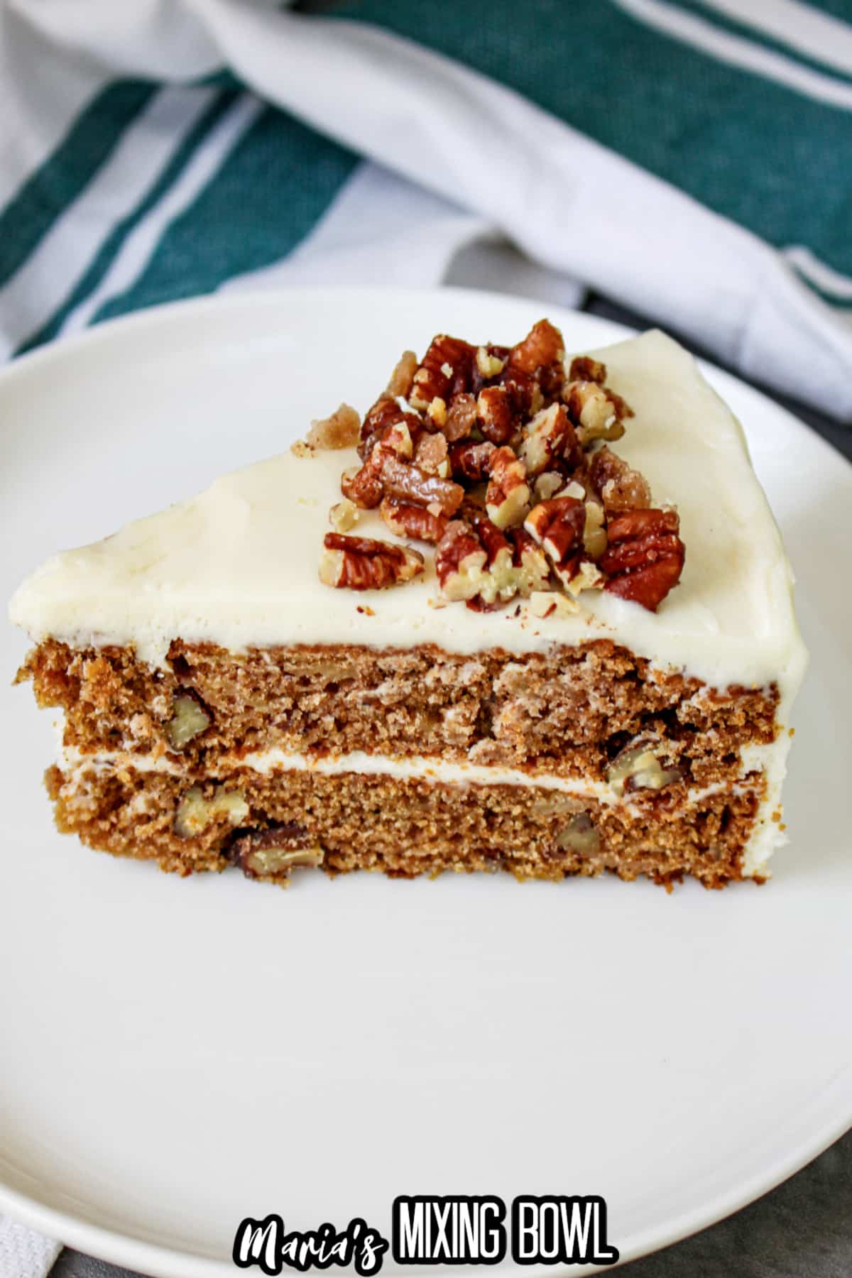 slice of apple spice cake topped with cream cheese frosting on a white plate.