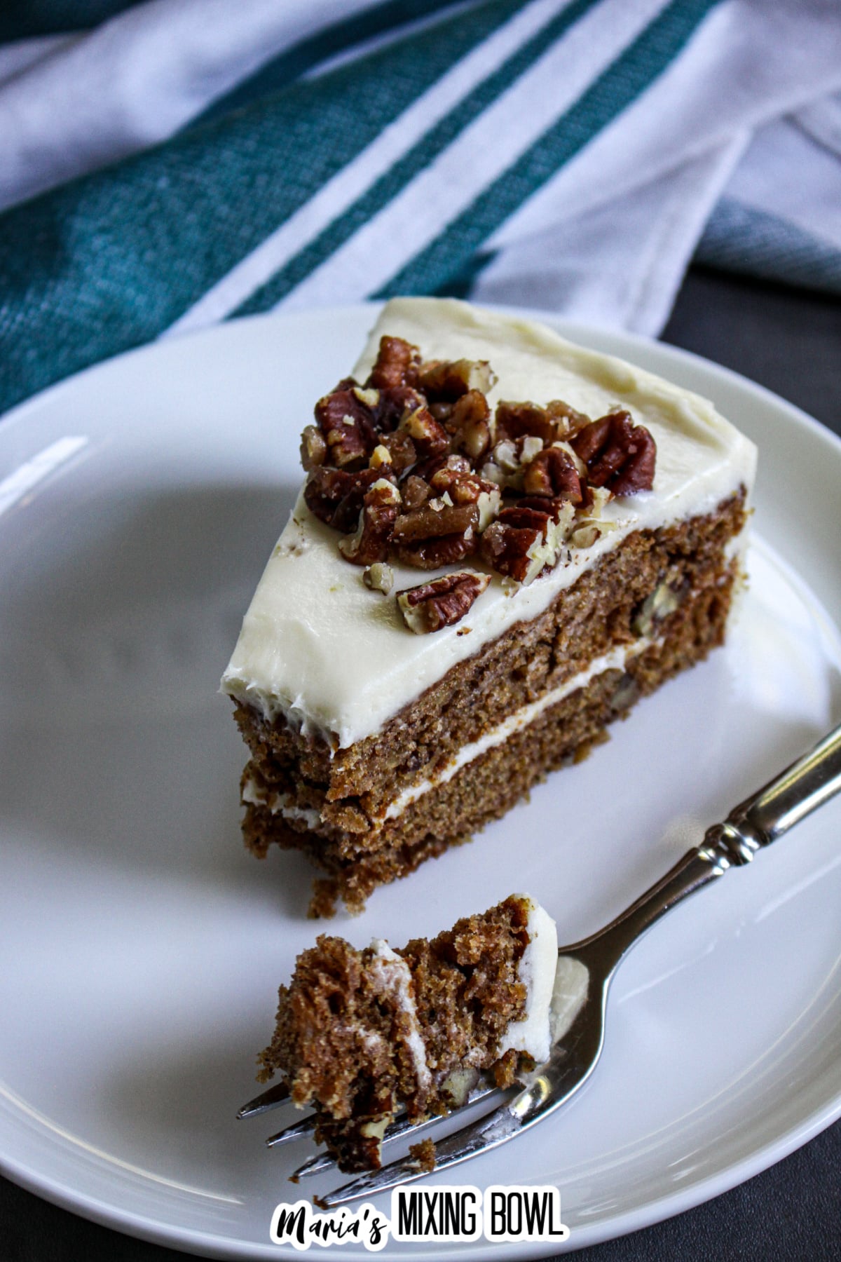 slice of apple spice cake with a bite missing on a plate.