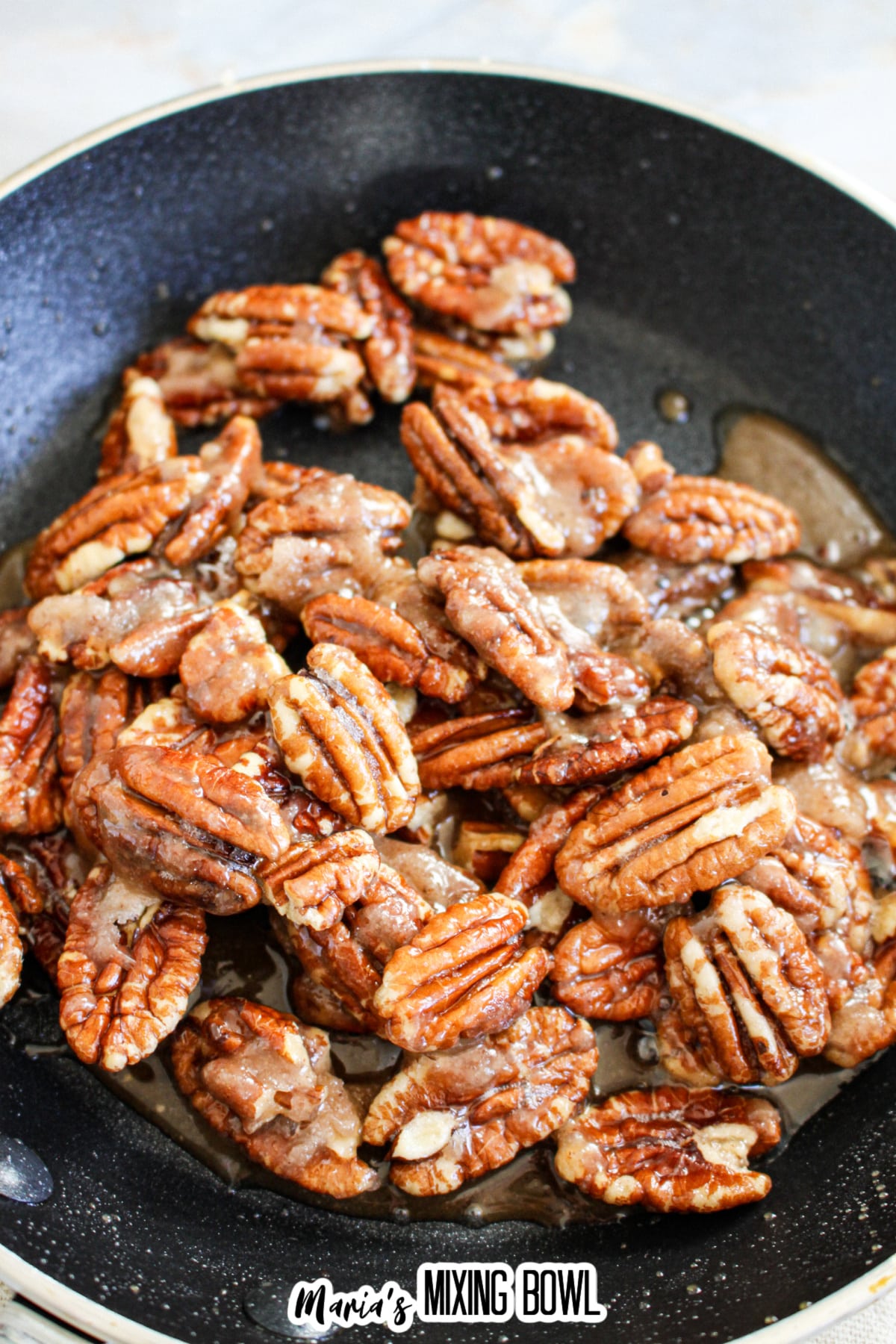 pecan halves being caramelized in a skillet.