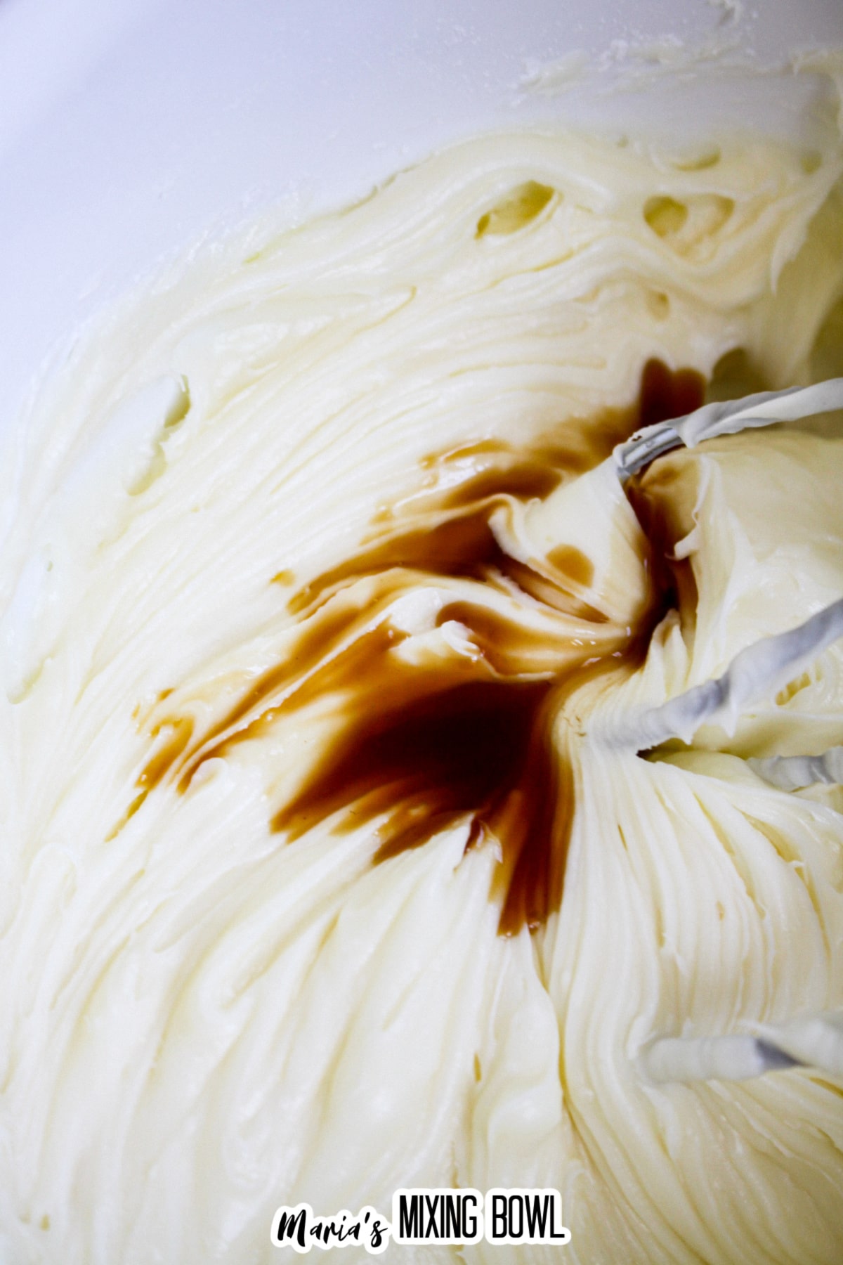 cream cheese frosting being mixed in a white plate.