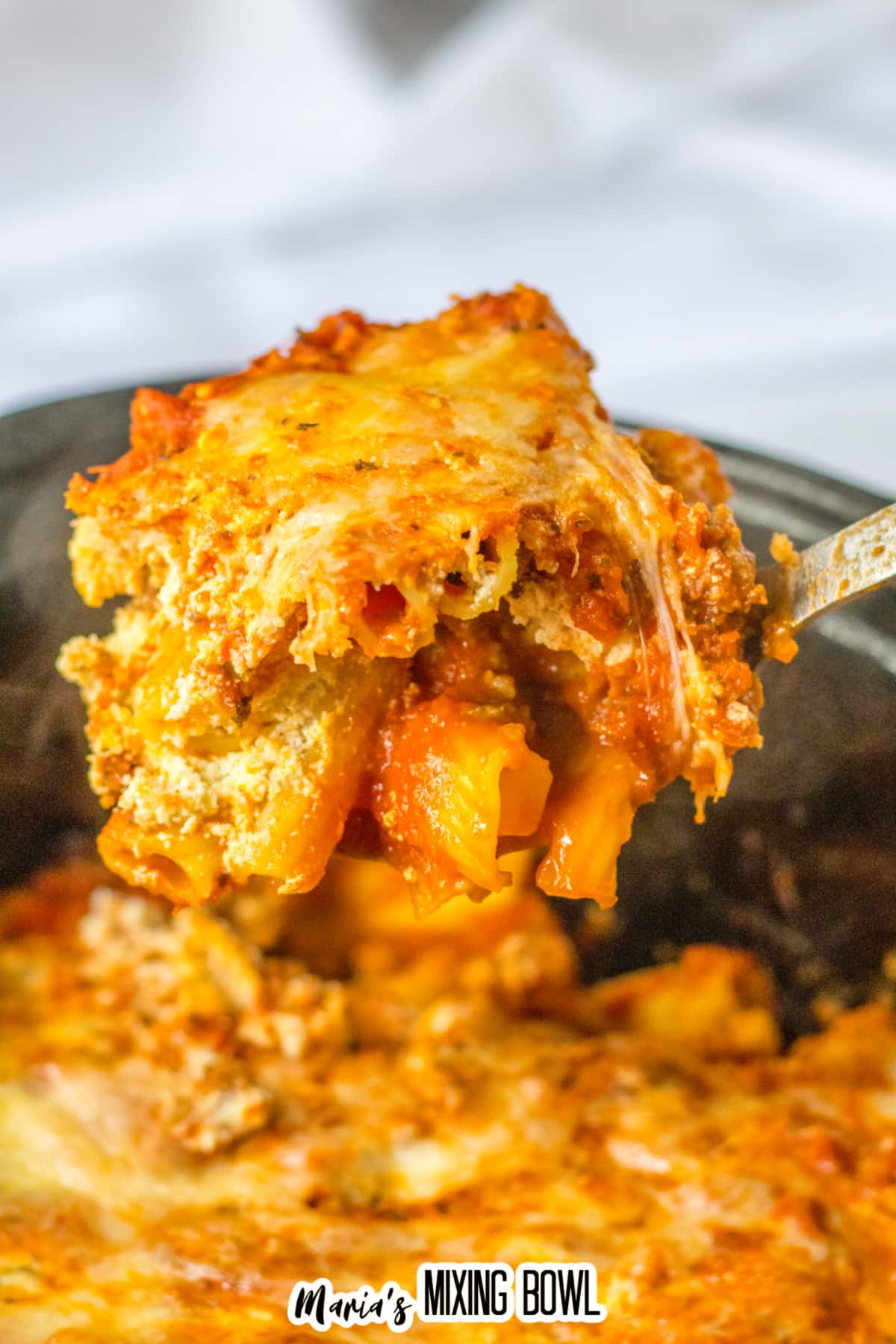 spoonful of baked ziti held above the slow cooker.