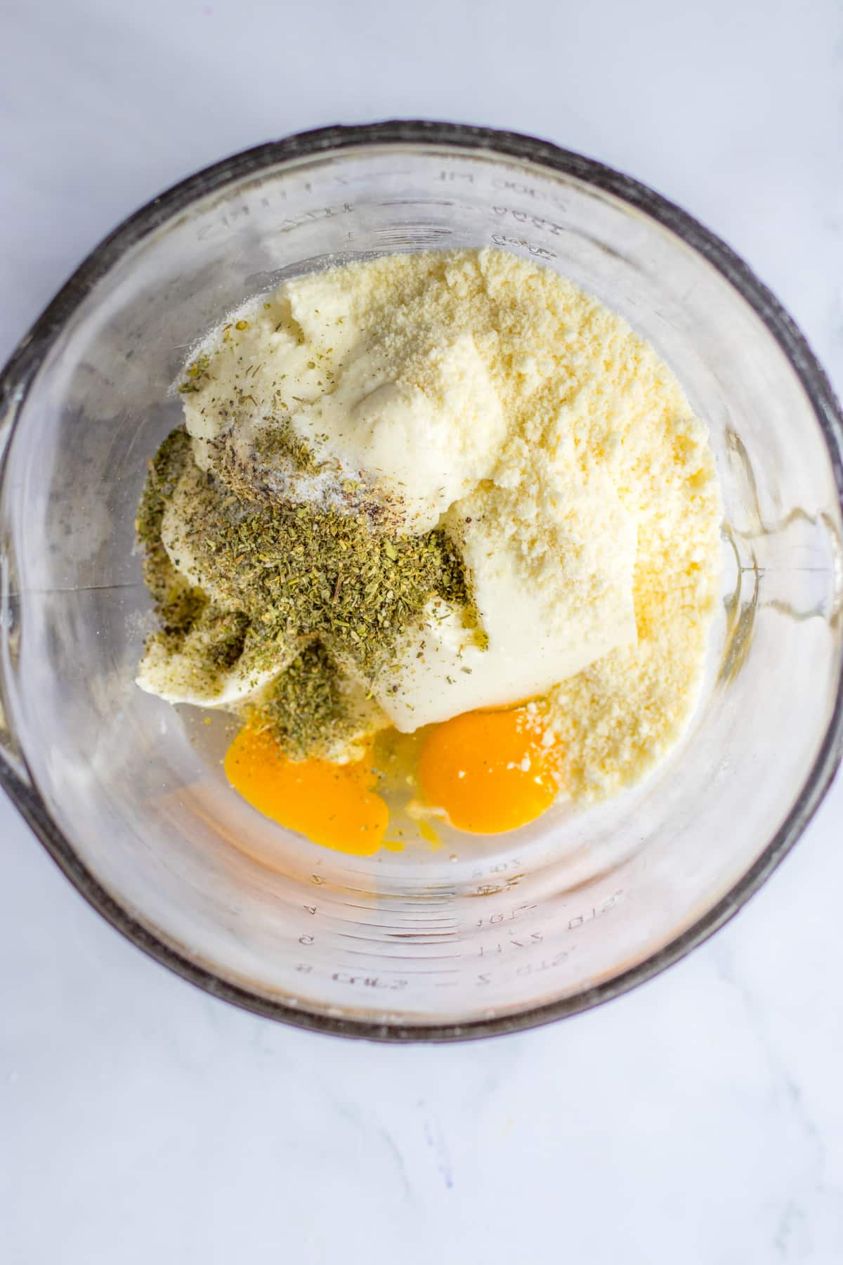 ricotta cheese, parmesan cheese, and raw eggs in a mixing bowl.