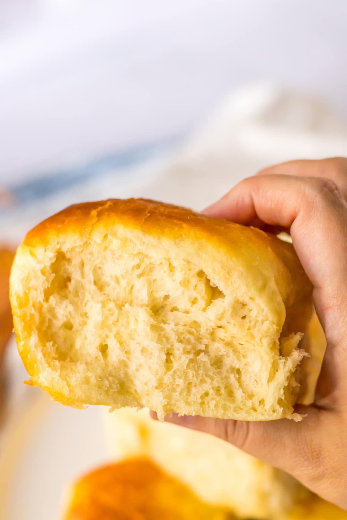 cafeteria roll held in the air in a woman's hand.