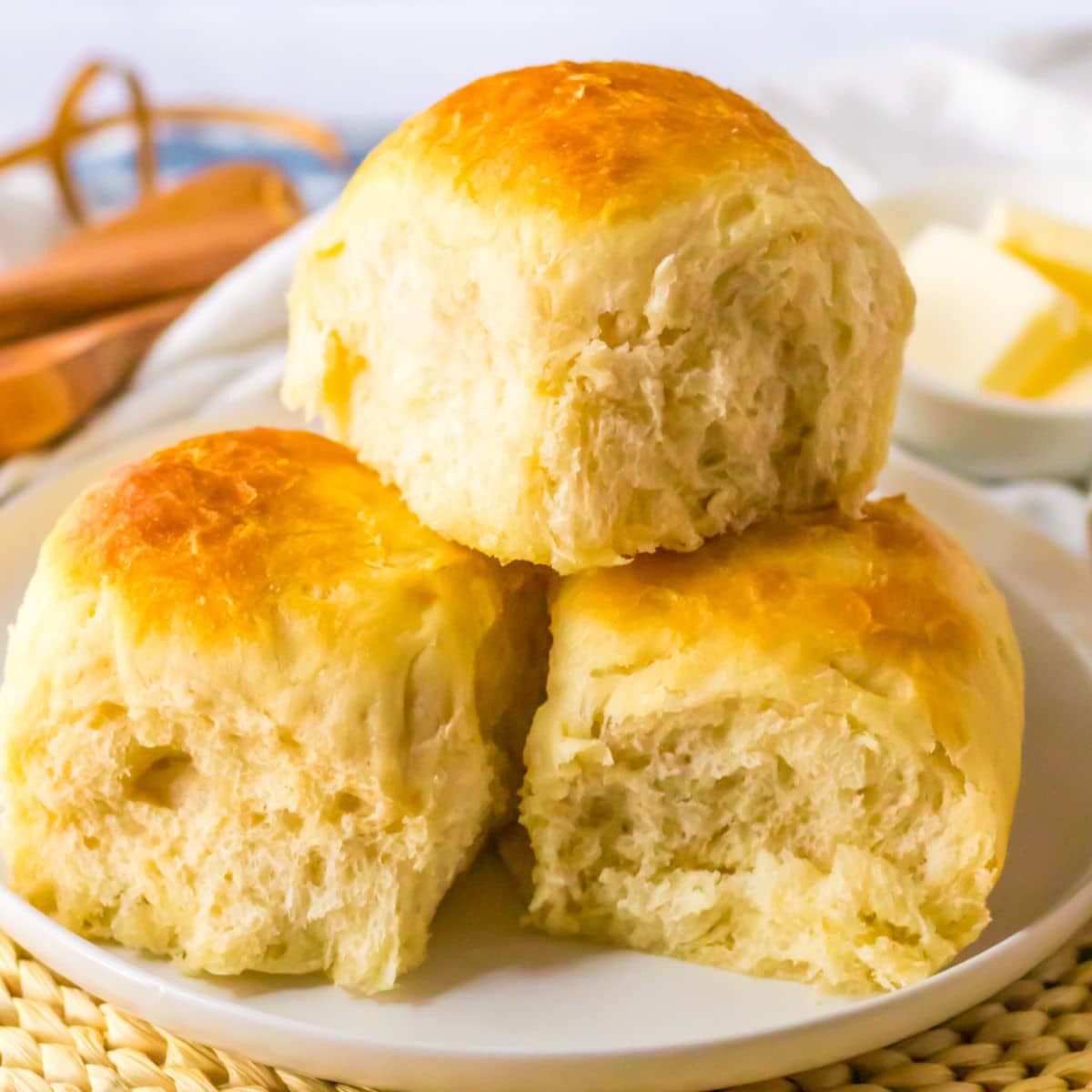 three cafeteria rolls stacked on a small plate.