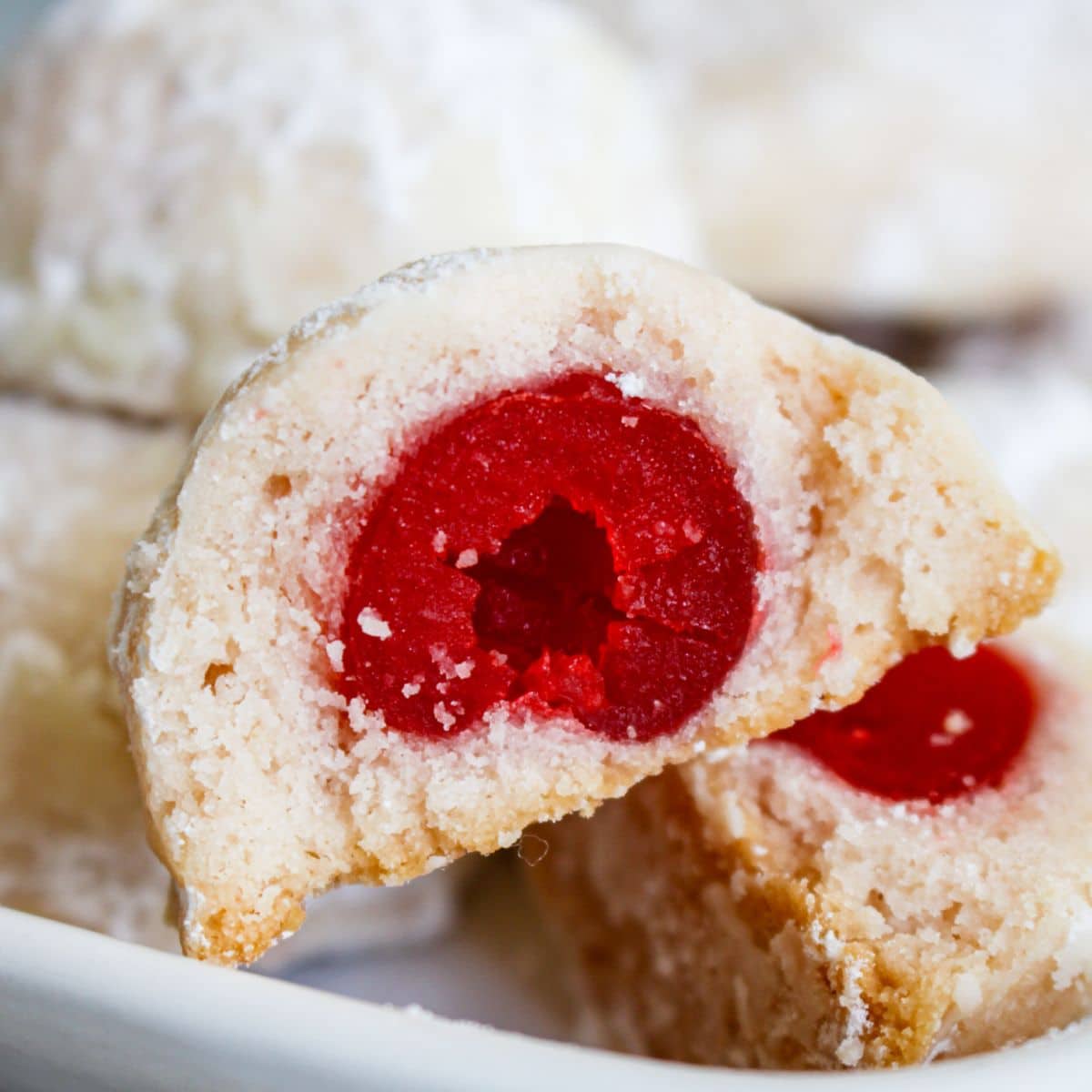 cherry snowball cookie broken open in half to show the cherry on the inside.