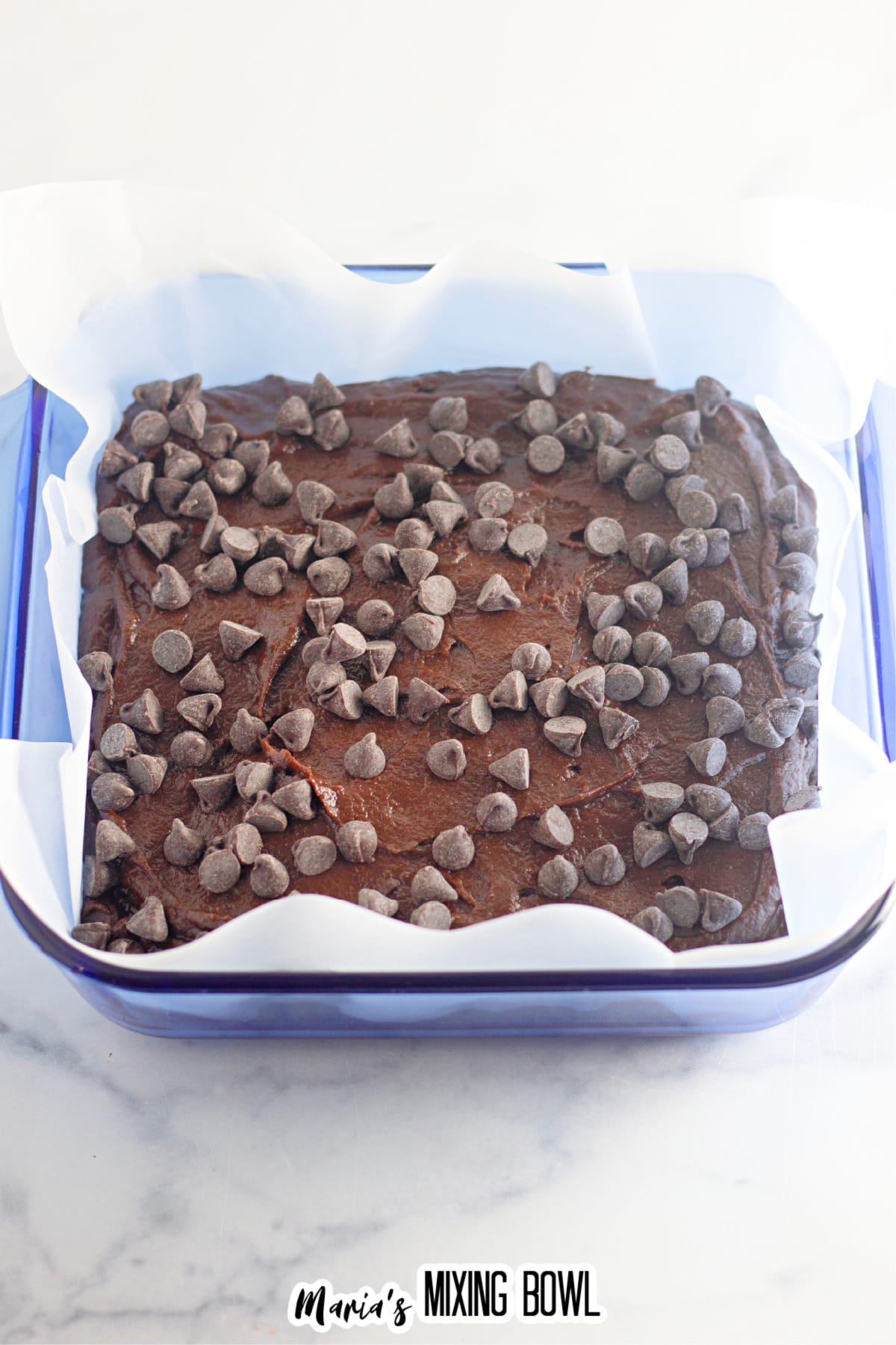 brownie batter in a parchment lined glass baking dish.