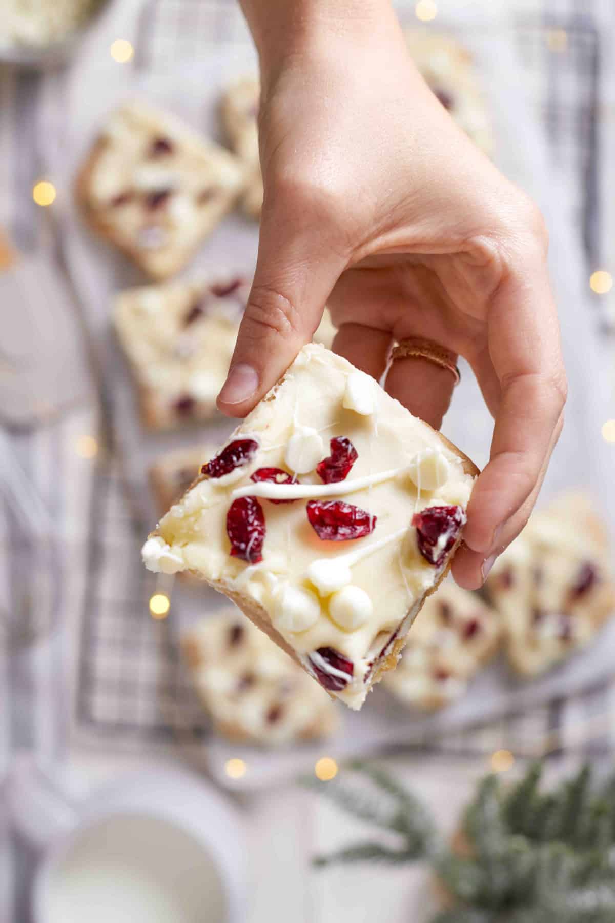 cranberry bliss bar held in the air in a woman's hand.