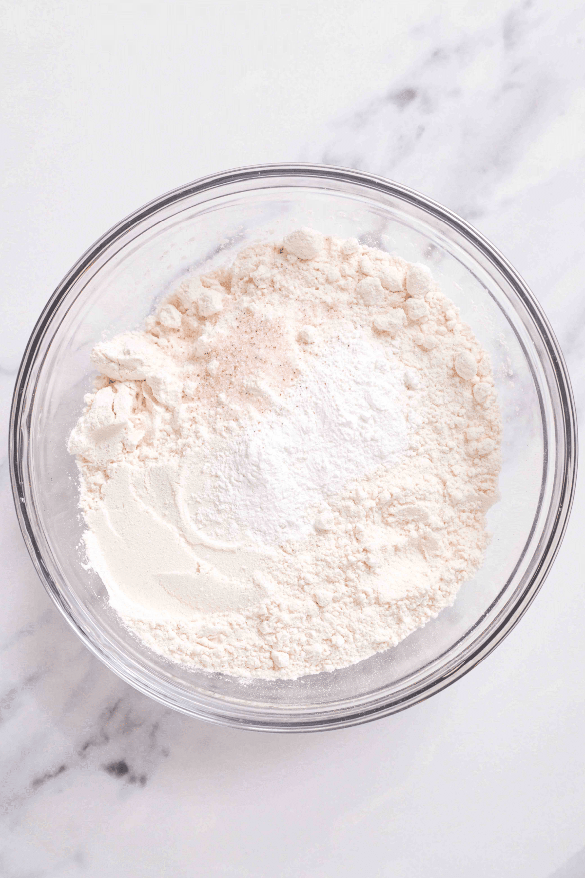 dry ingredients being mixed in a glass bowl.