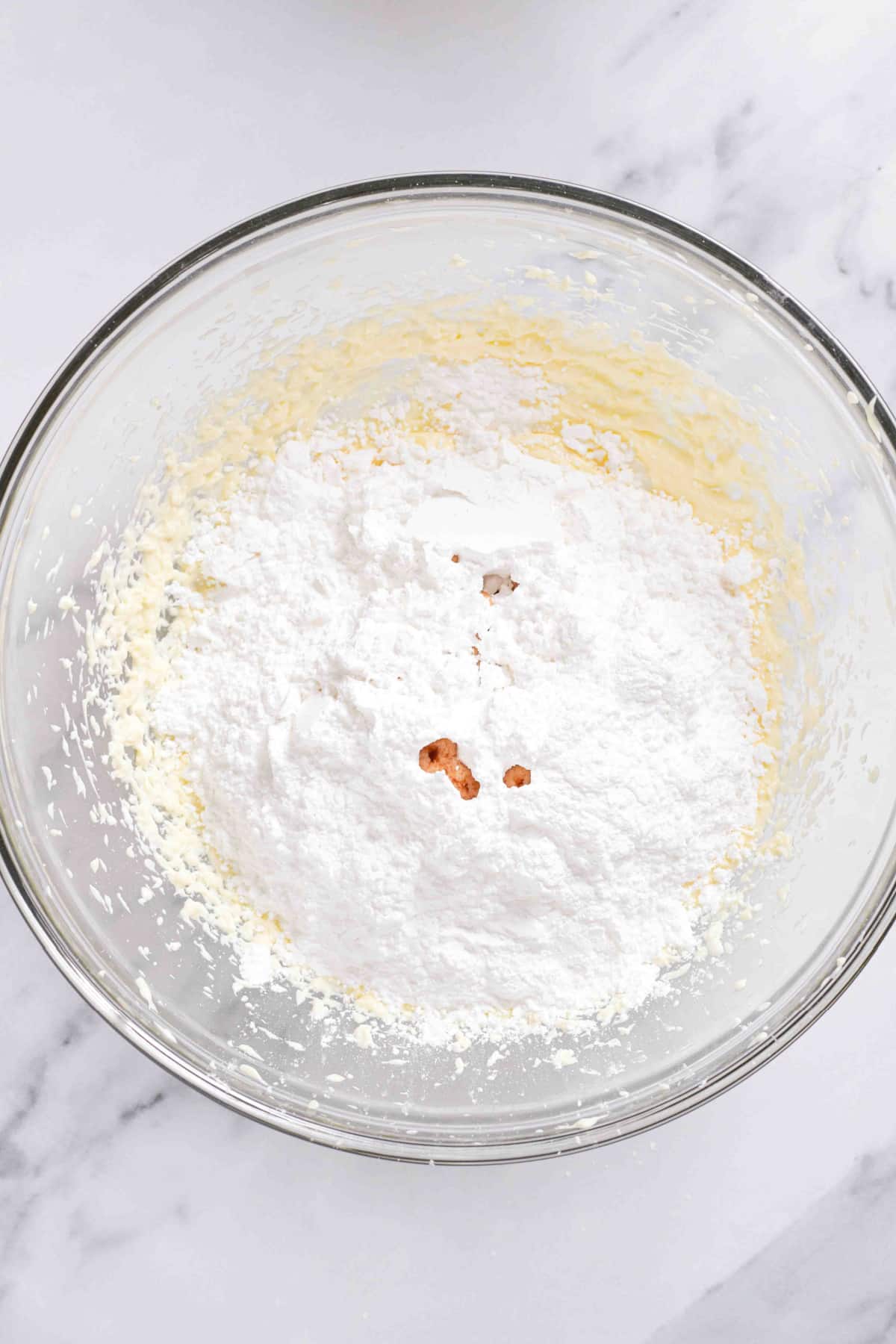 cream cheese frosting being mixed in a glass bowl.
