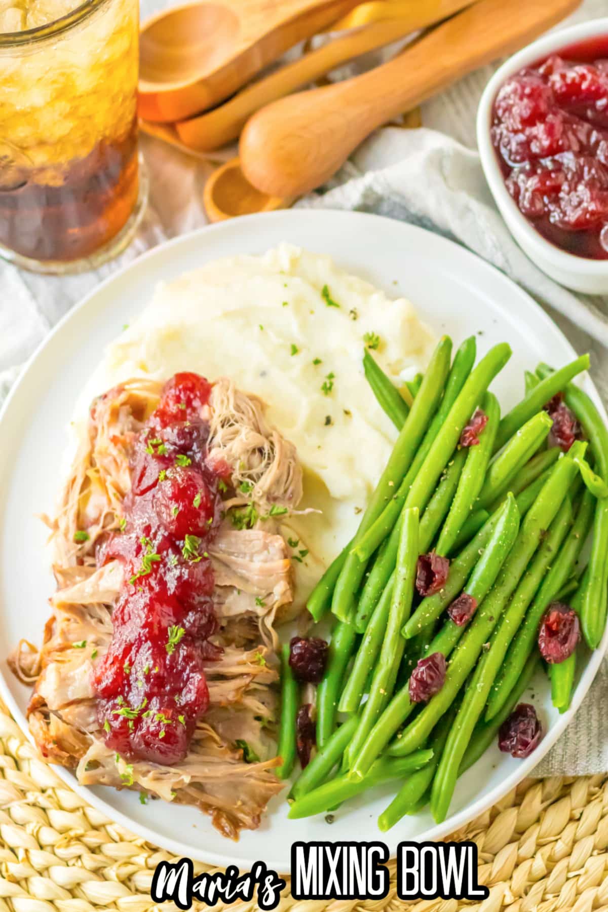 cranberry roast pork loin on a plate with mashed potatoes and green beans.