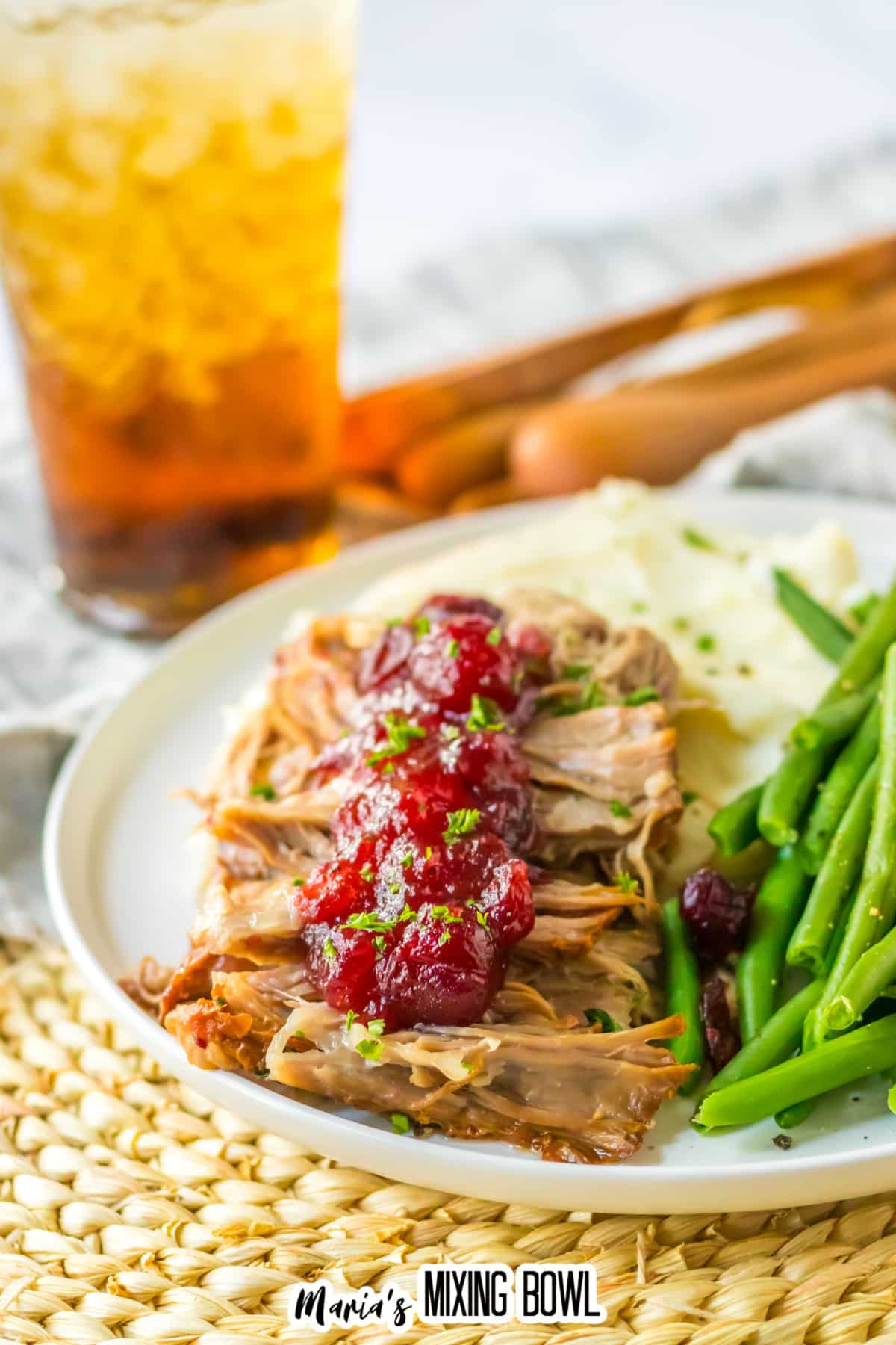 cranberry roast pork loin on a plate with mashed potatoes and green beans.