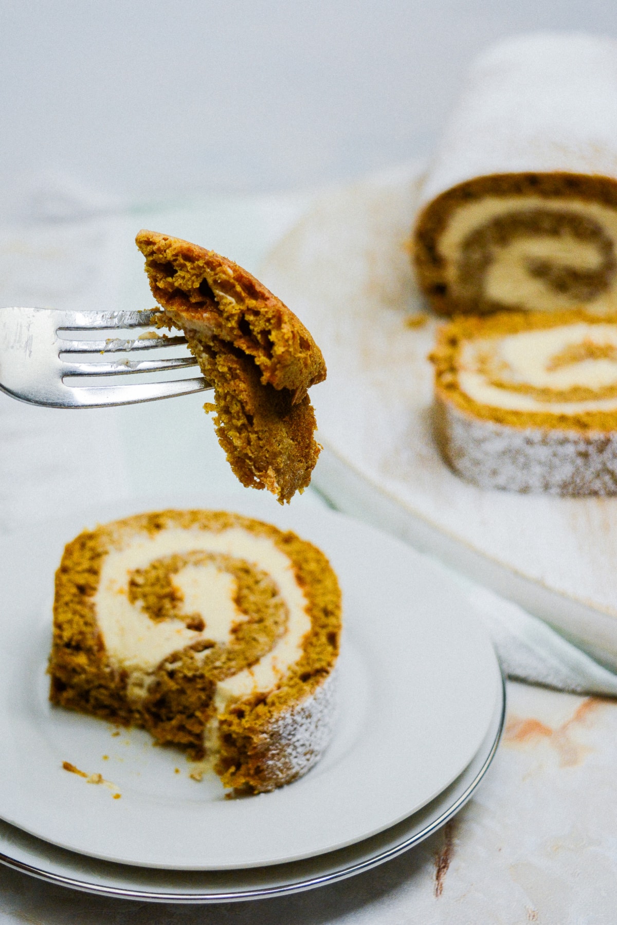 bite of gingerbread cake roll on a fork held in the air.