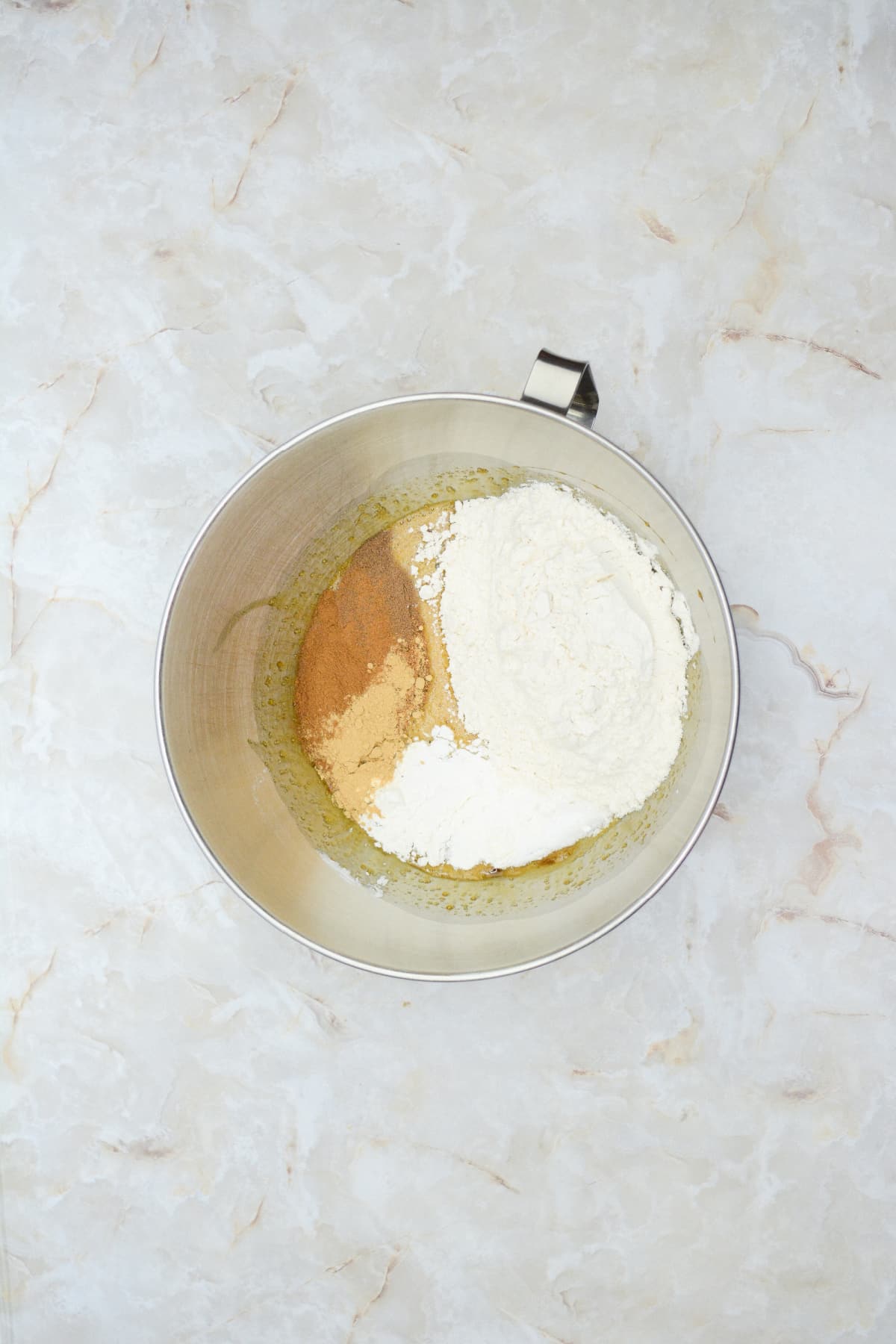 dry ingredients being added to wet ingredients in a mixing bowl.