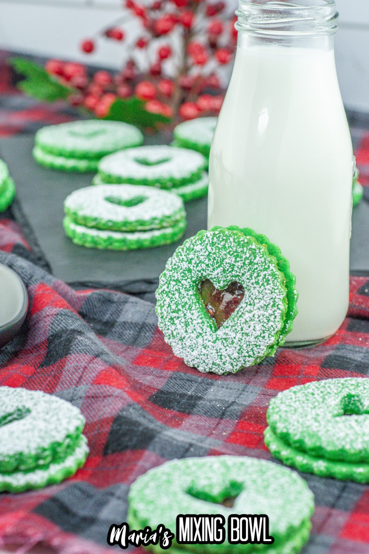 grinch linzer cookie leaning against a glass of milk.