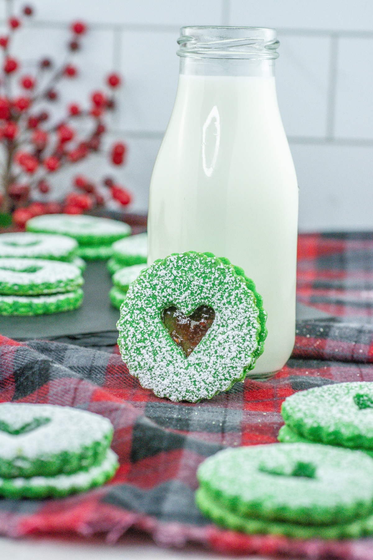 grinch linzer cookie leaning against a glass of milk.