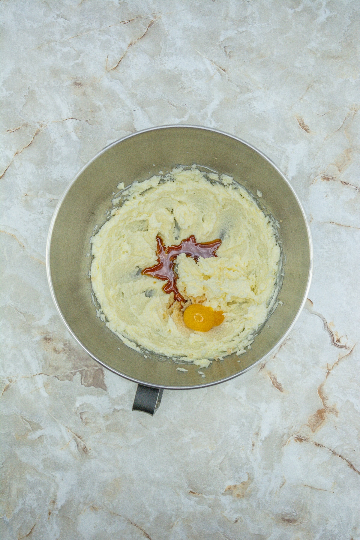 butter, sugar, vanilla and eggs being creamed in a mixing bowl.