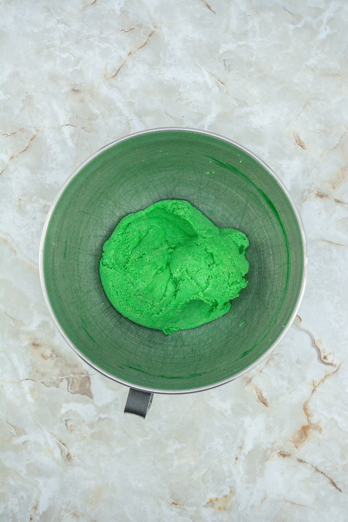 green cookie dough ball in a stainless steel mixing bowl.