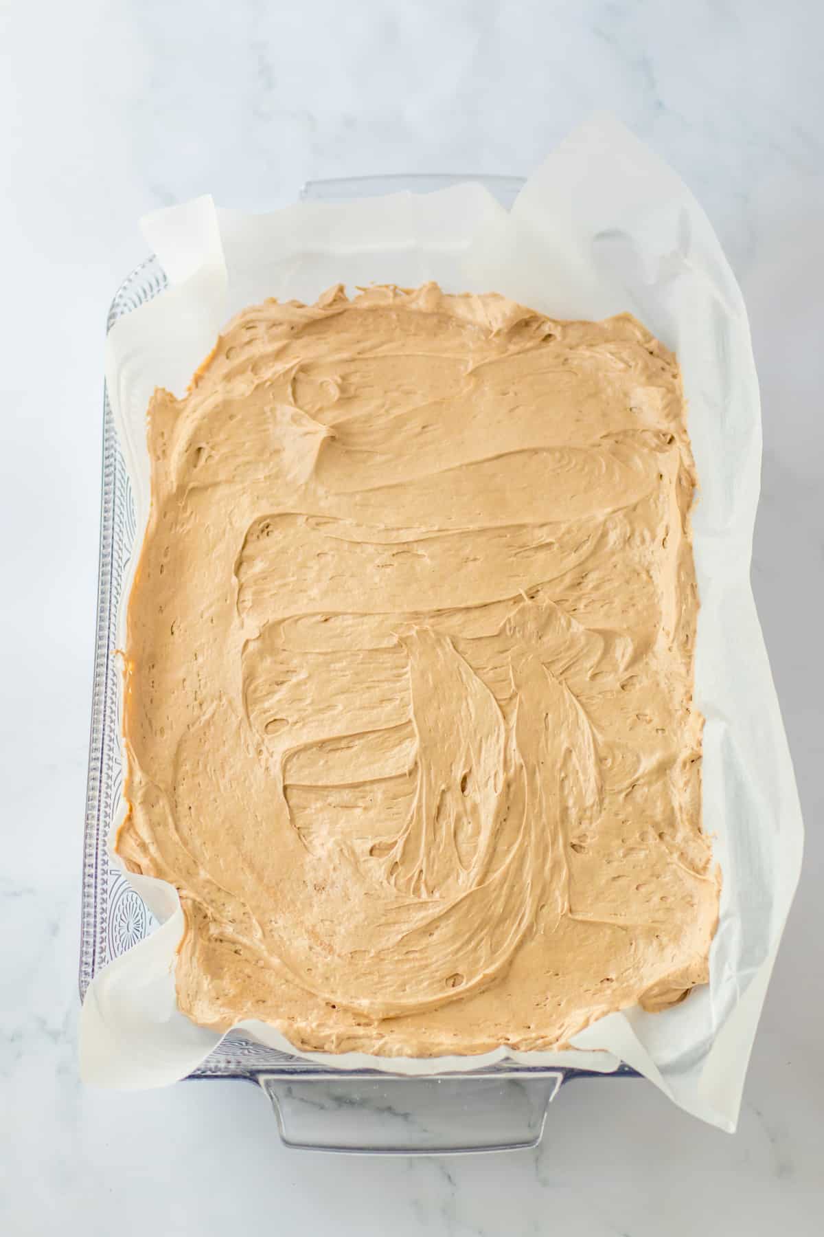 chocolate cream cheese layer being spread in a baking dish.