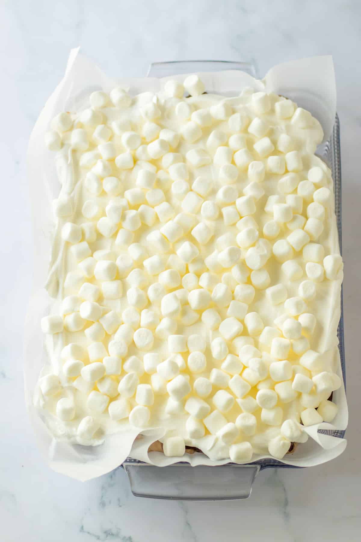 marshmallows on top of a hot chocolate lush in a glass baking dish.