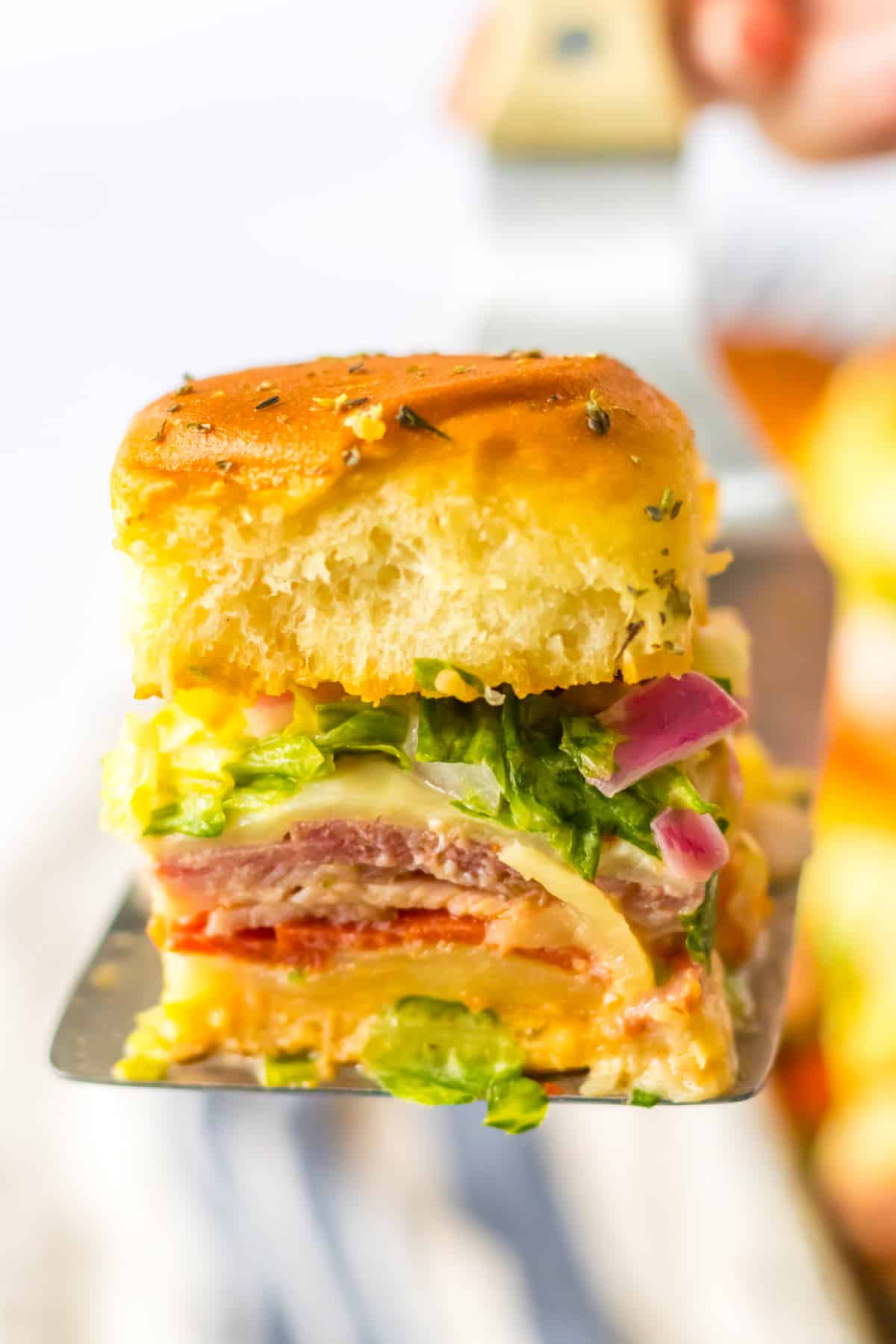 italian sub slider on a metal spatula held in the air.