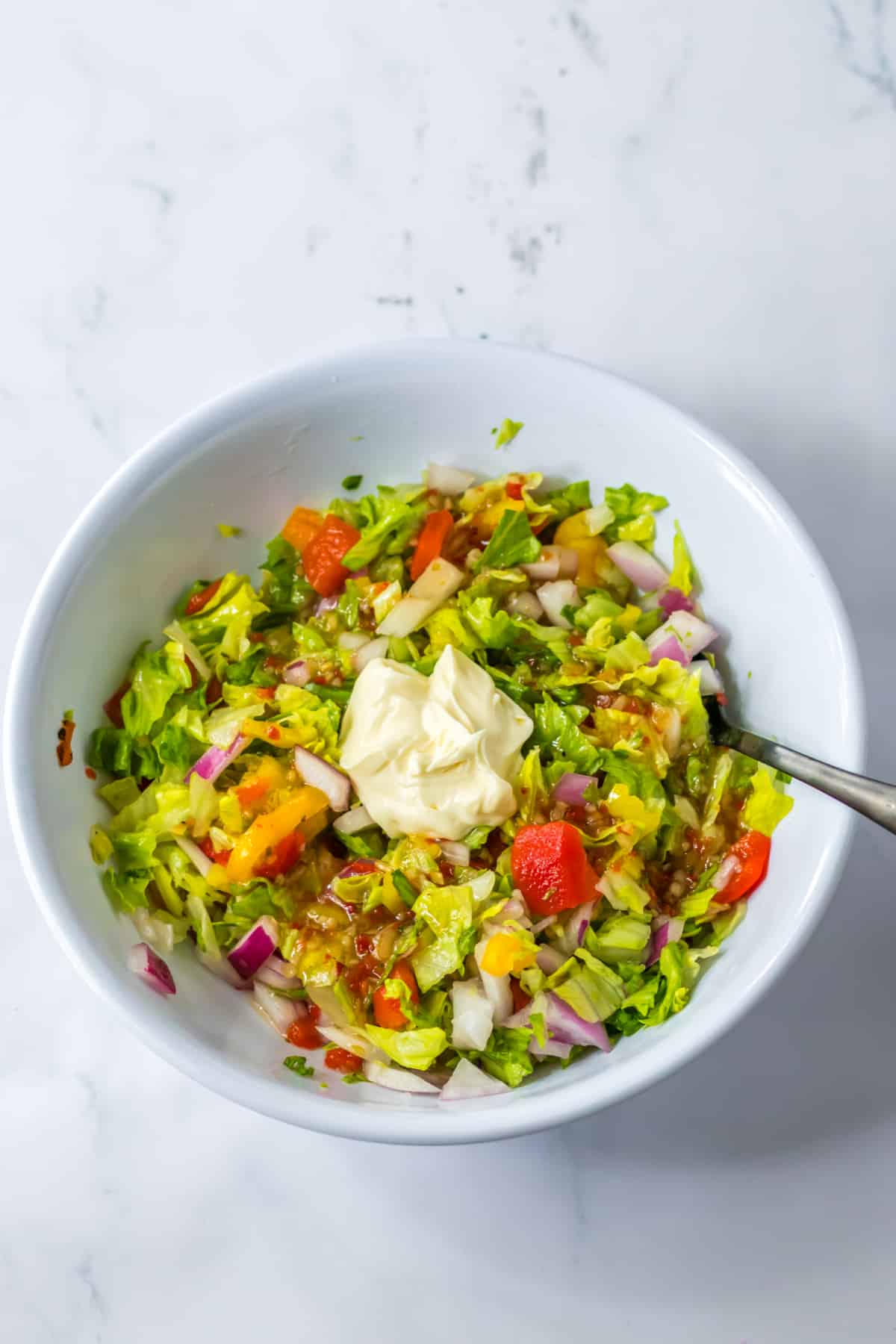 vegetables and mayo being mixed together in a bowl.